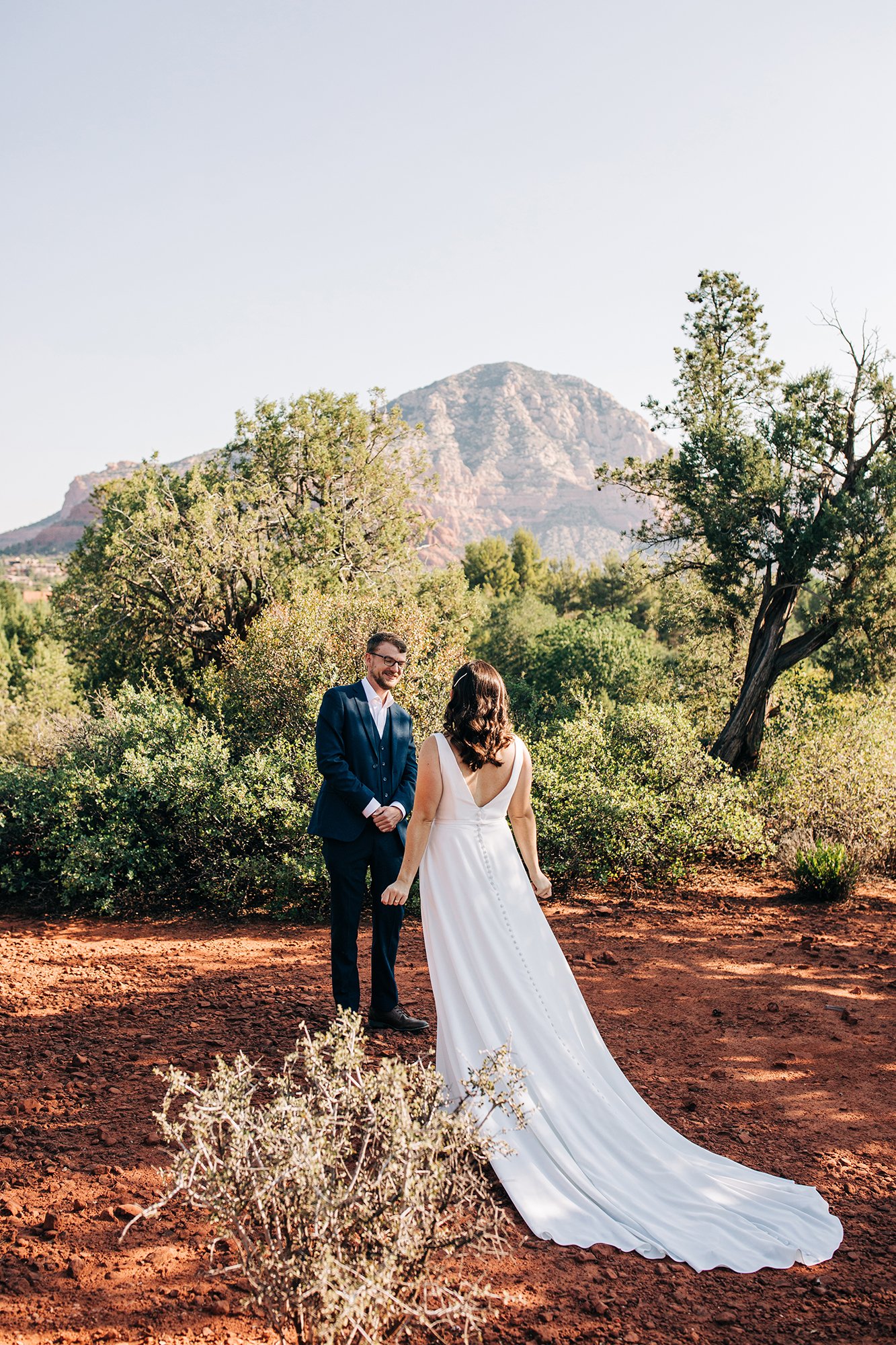 Stephanie and Matthew share a first look moment amongst trees and red rocks. 