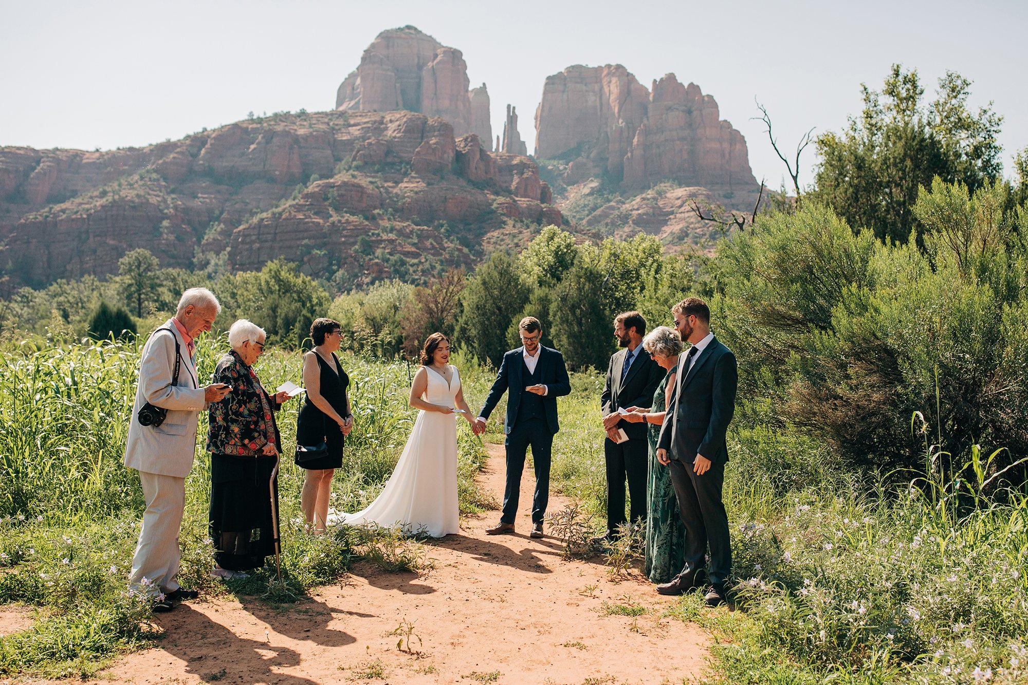 Stephanie and Matthew are surrounded by family on their wedding day, the towering cliffs of Sedona stand in the background