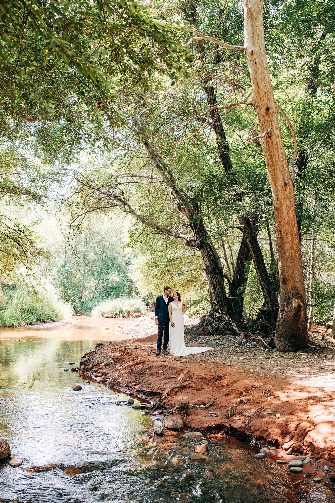 Stephanie and Matthew pose for their Sedona wedding photographer next to a lovely stream