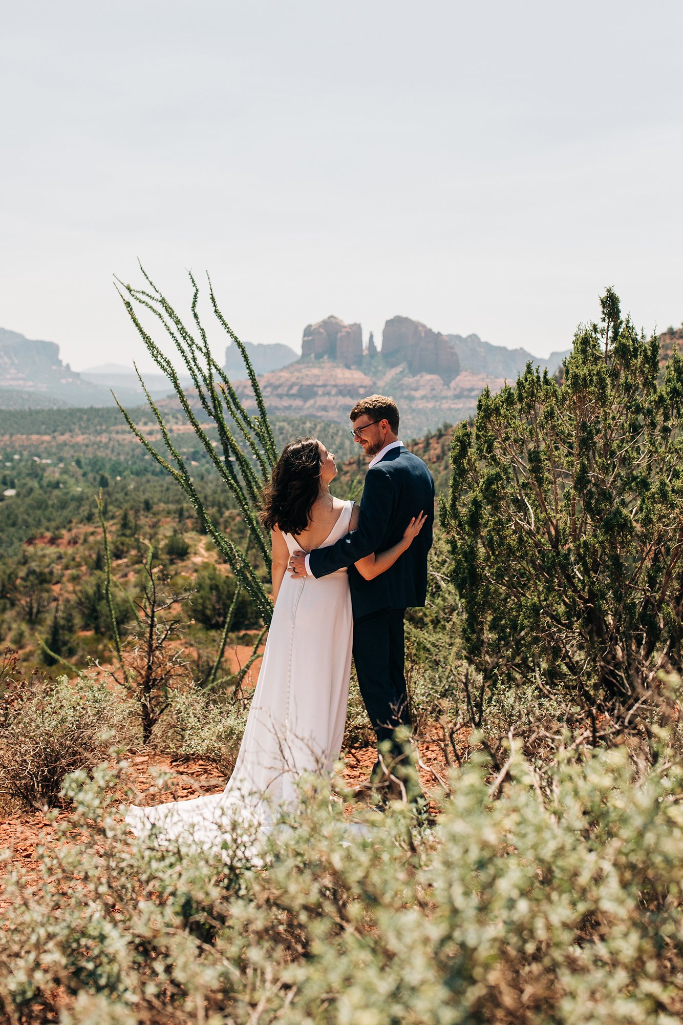 With amazing cliffs and dazzling plants in the background, Matt and Steph pose in their wedding attire for elopement photographer in Sedona