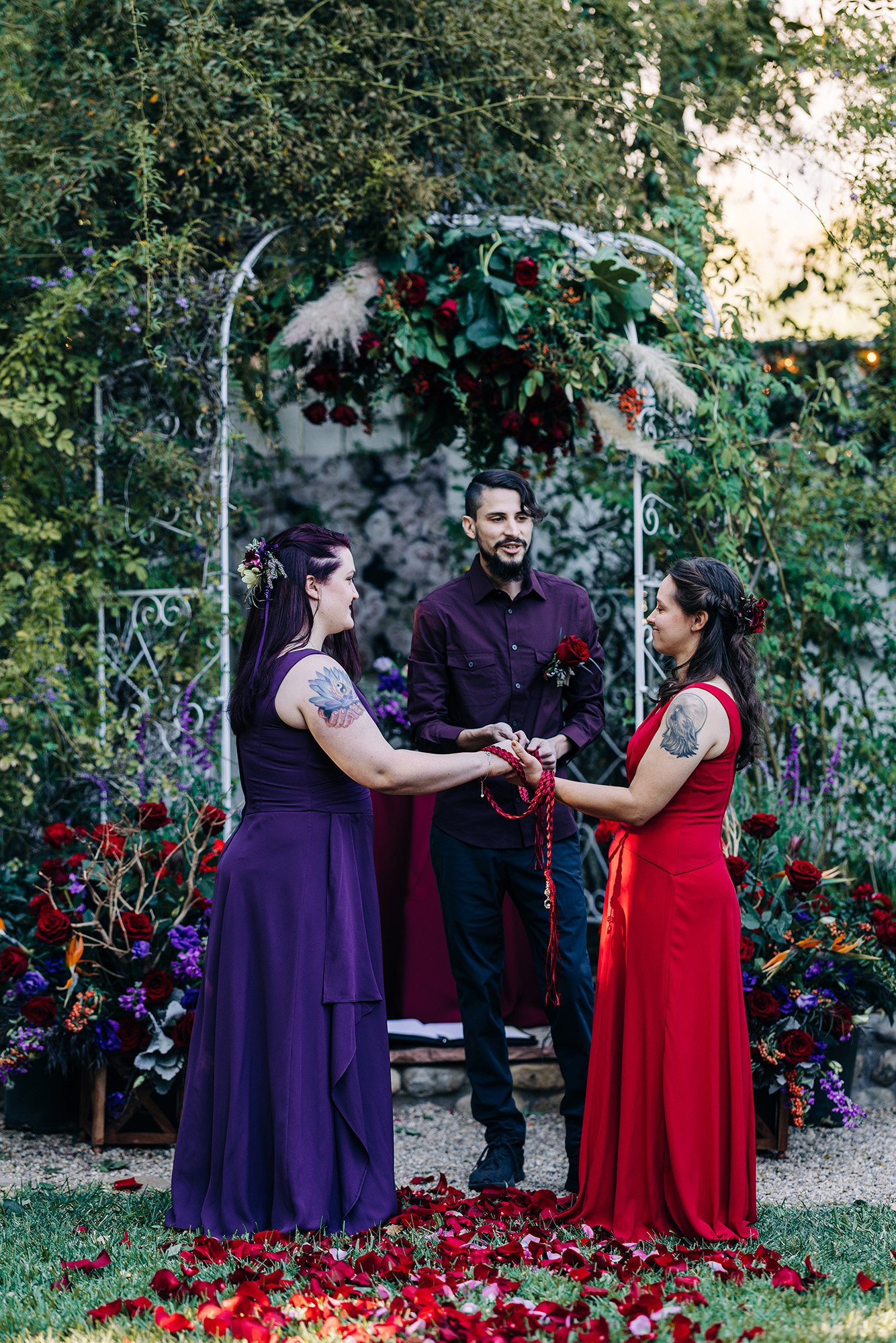 Our wedding officiant, Isiah, wraps a red cord around Heather and Veronica's hands during their wedding day.