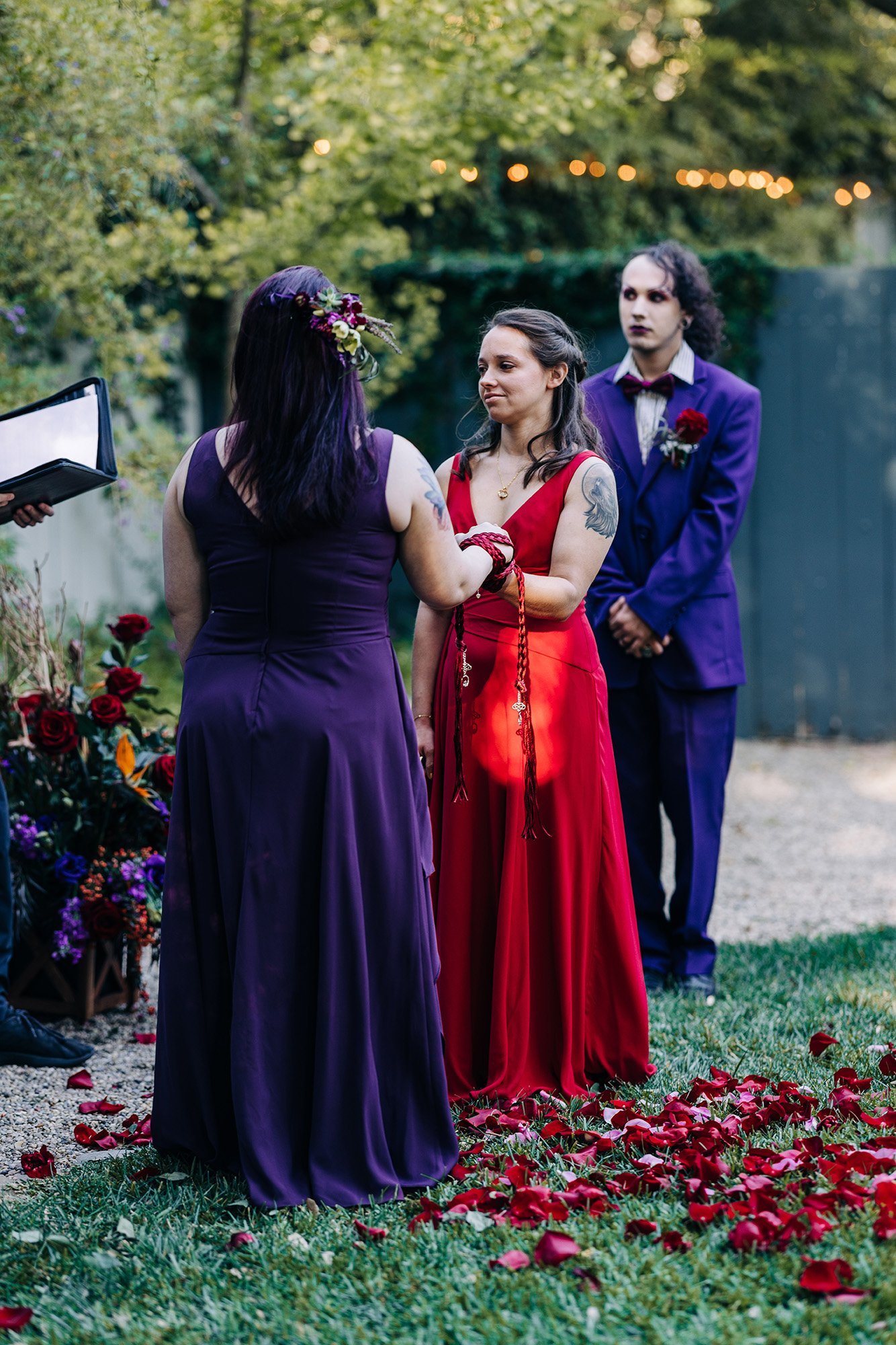 Heather and Veronica, dressed in purple and red dresses, share their wedding vows during this handfasting ceremony.