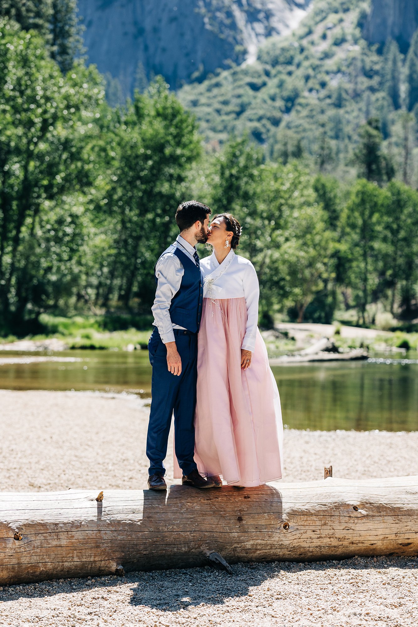 Yooree and Jarrod kiss on a log during their elopement in Yosemite National Park, California.