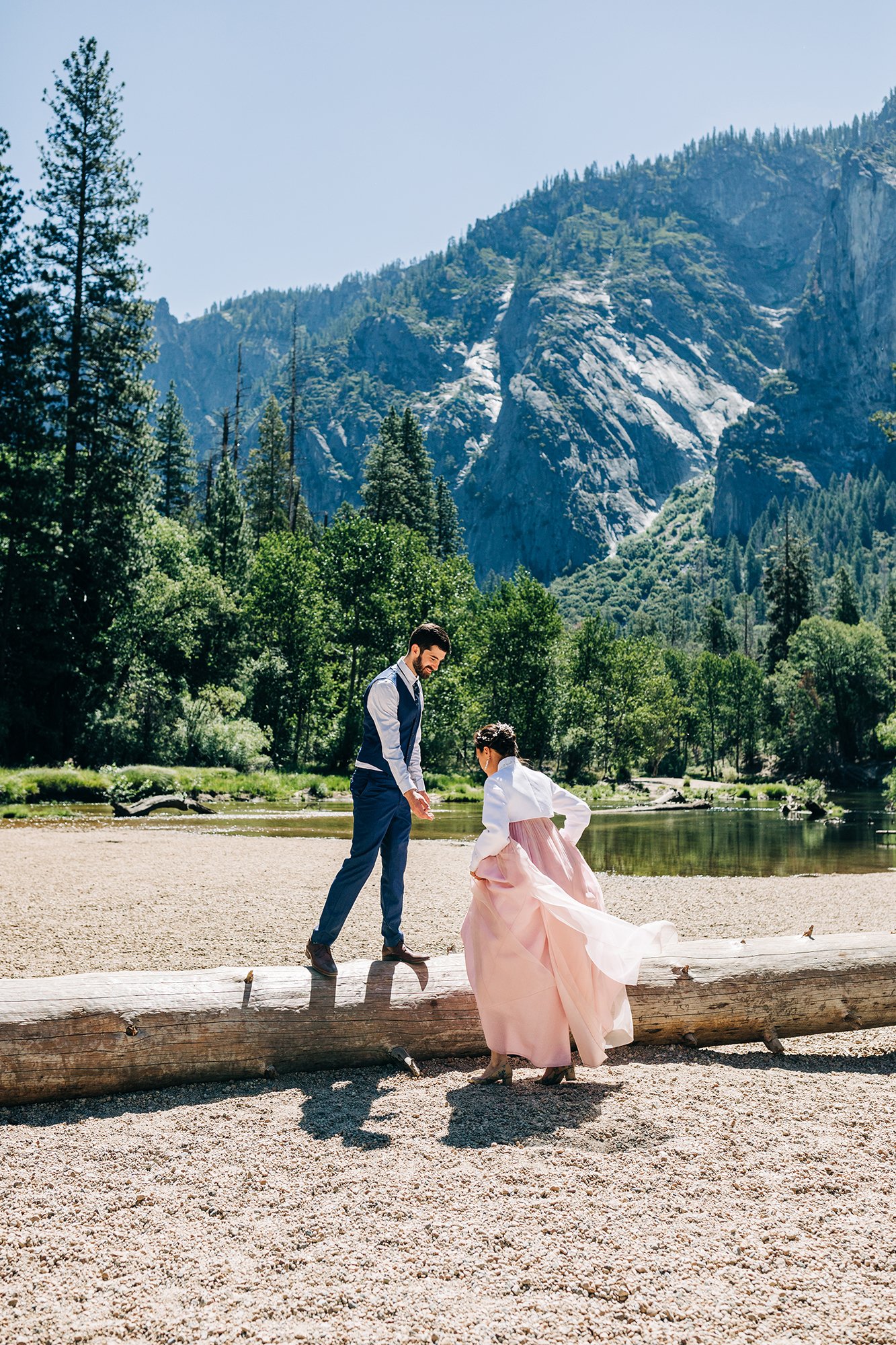 Yooree and Jarrod climb onto a log during their elopement in Yosemite National Park, California.