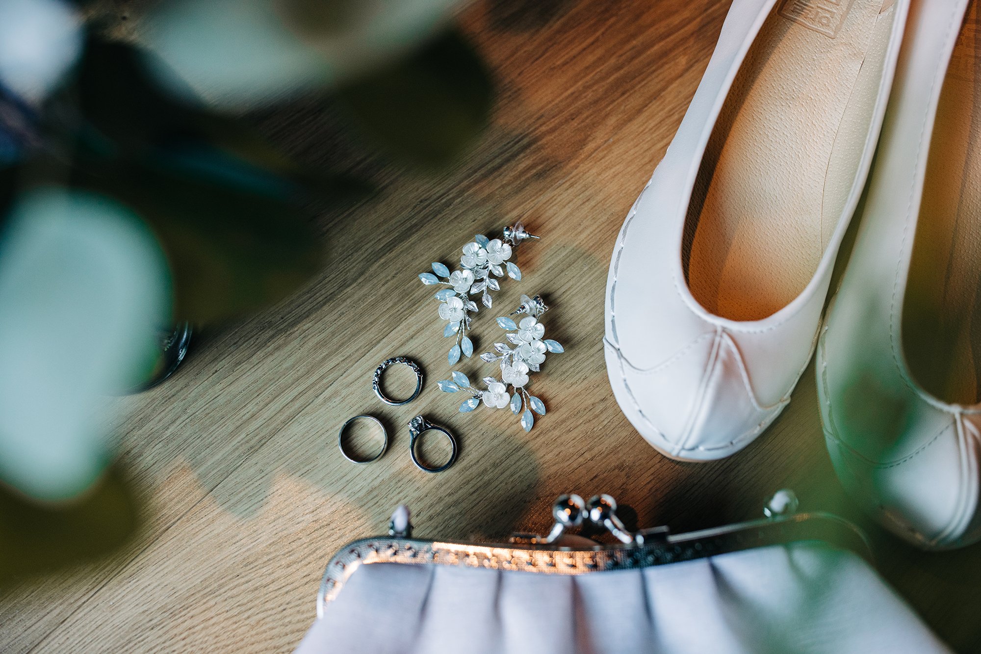 A flat lay of wedding rings, shoes, and jewelry. 