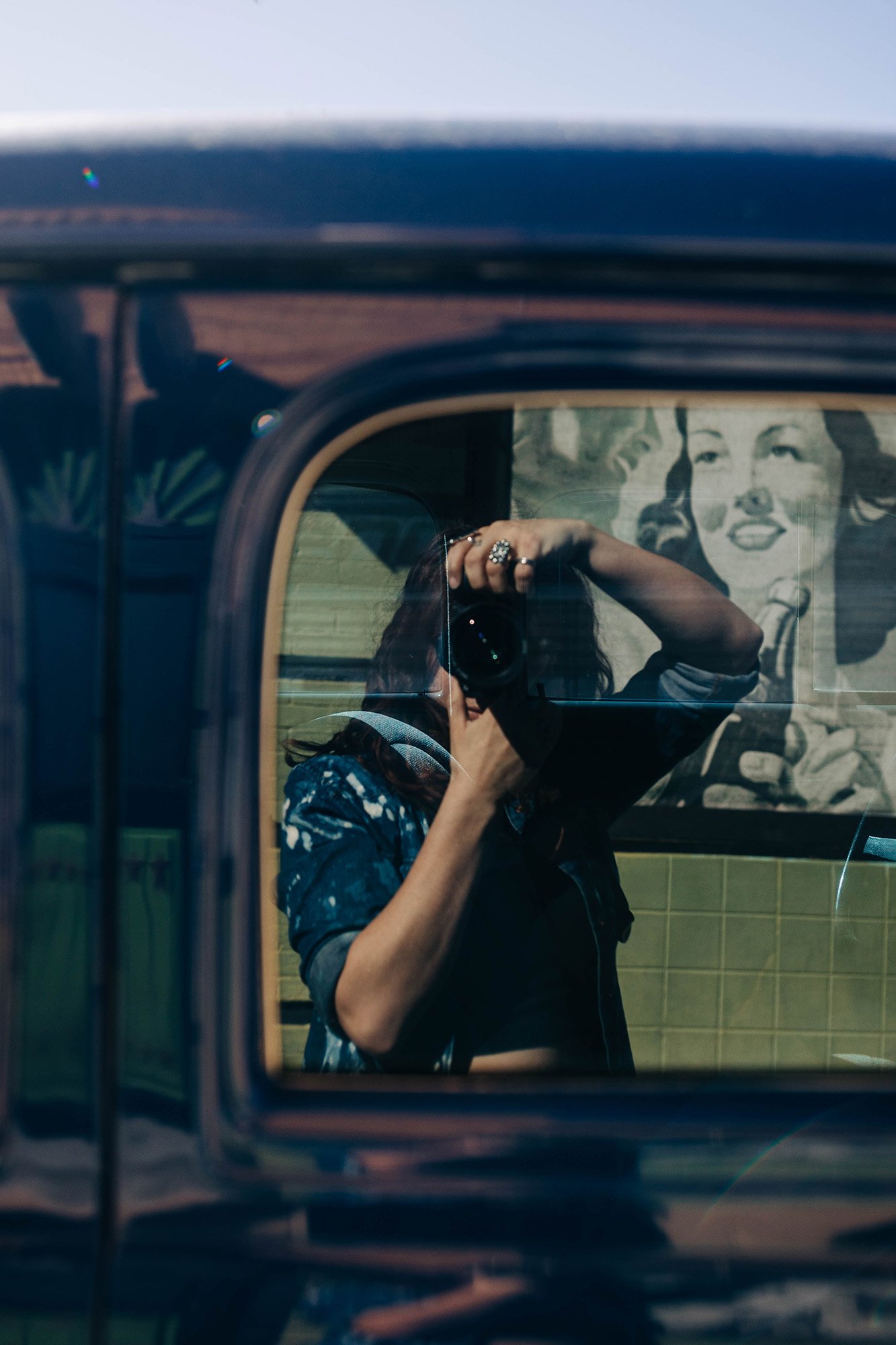 A photographer's reflection in a retro car.  