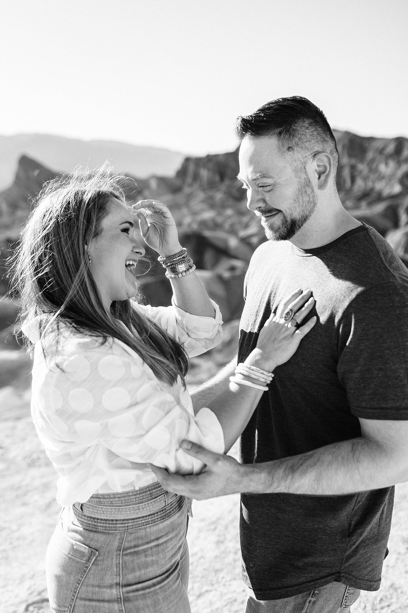 A black and white photo of Aly and Alex laughing together in the desert.