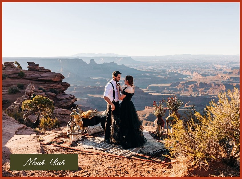 A wedding couple standing at the top of a lookout as one fixes the other's tie. 