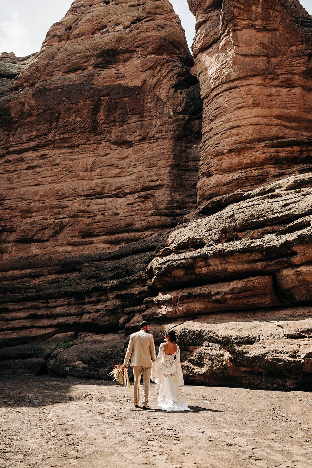 A couple in wedding attire walks through a slot canyon in New Mexico during their elopement. 