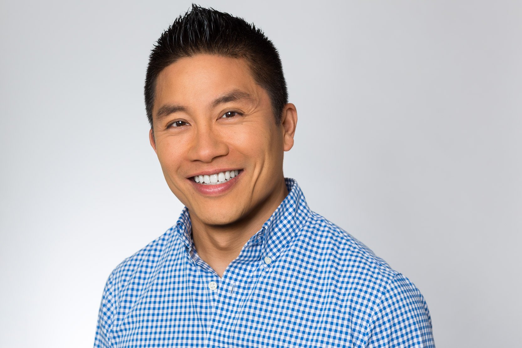 Smiling man with black hear wearing a patterned dress shirt in a headshot