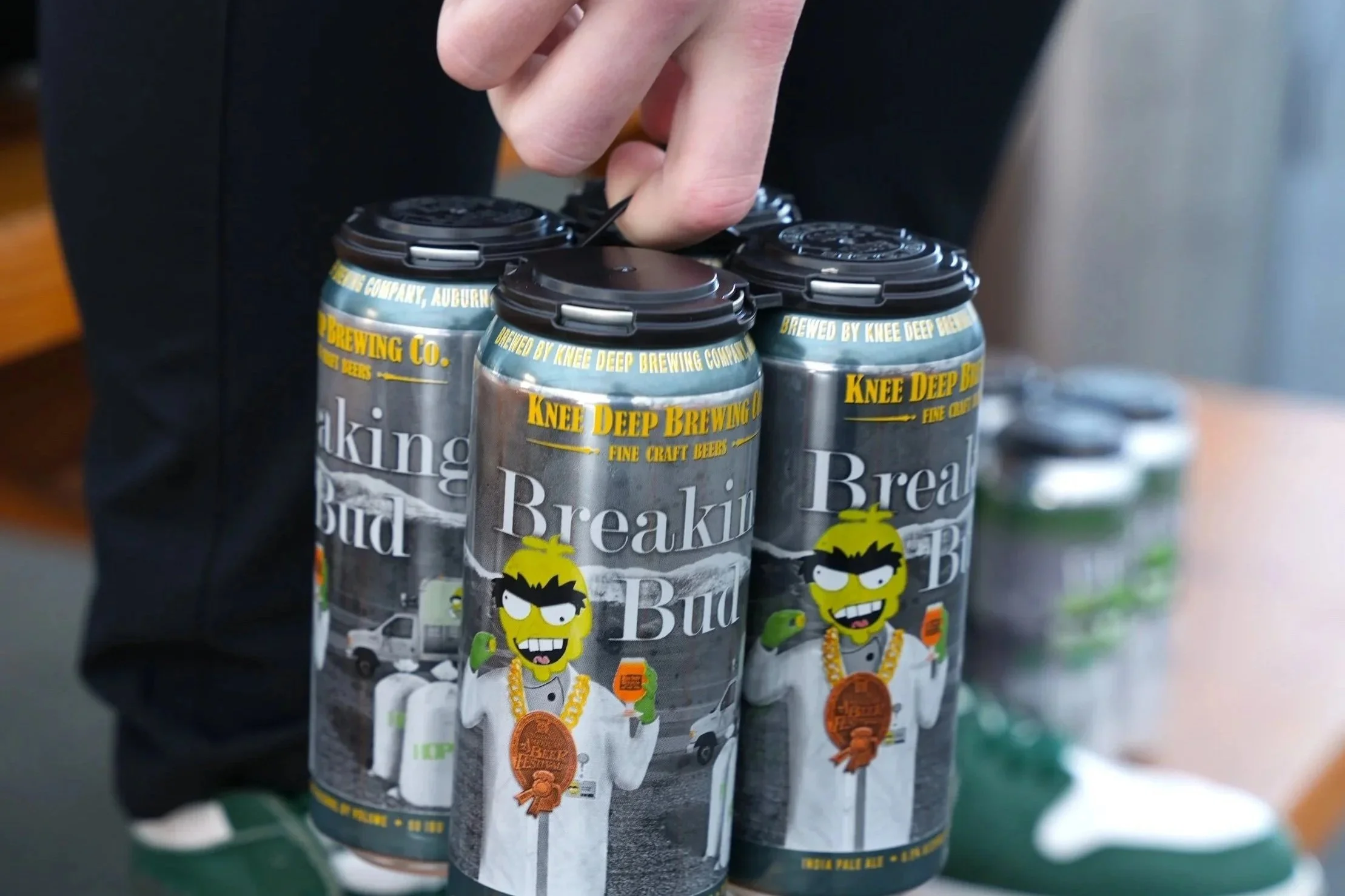 A person holding a pack of Knee Deep Brewing's Breaking Bud Craft Beer