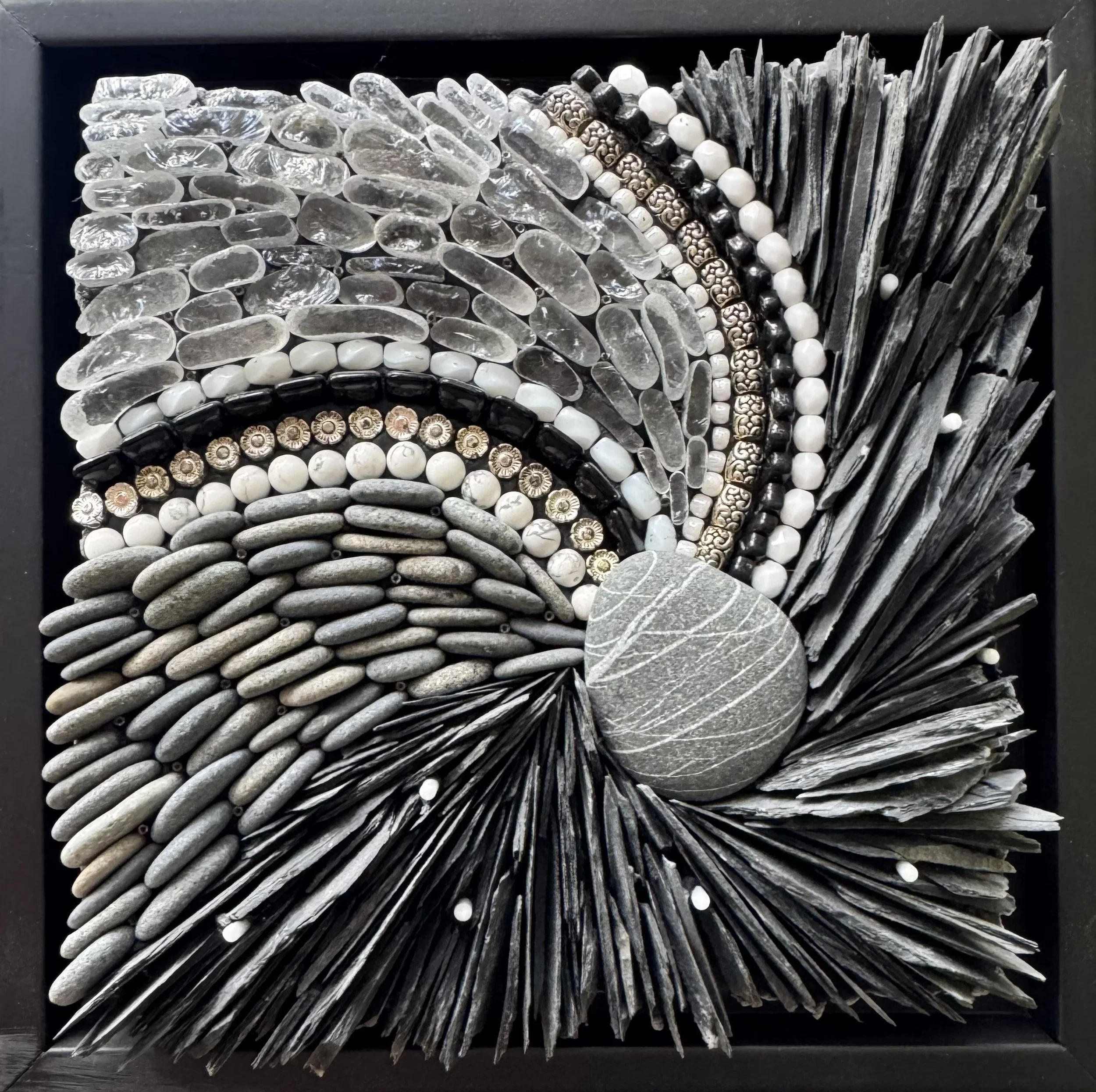 "Dance" - Central beach pebble of greywacke sandstone crosscut by fine veins of quartz. Slate from repurposed roofing tiles, beach pebbles, beach glass, glass beads, tiles and rods, metal beads, semi-precious howlite beads. 7.5" x 7.5". Available.