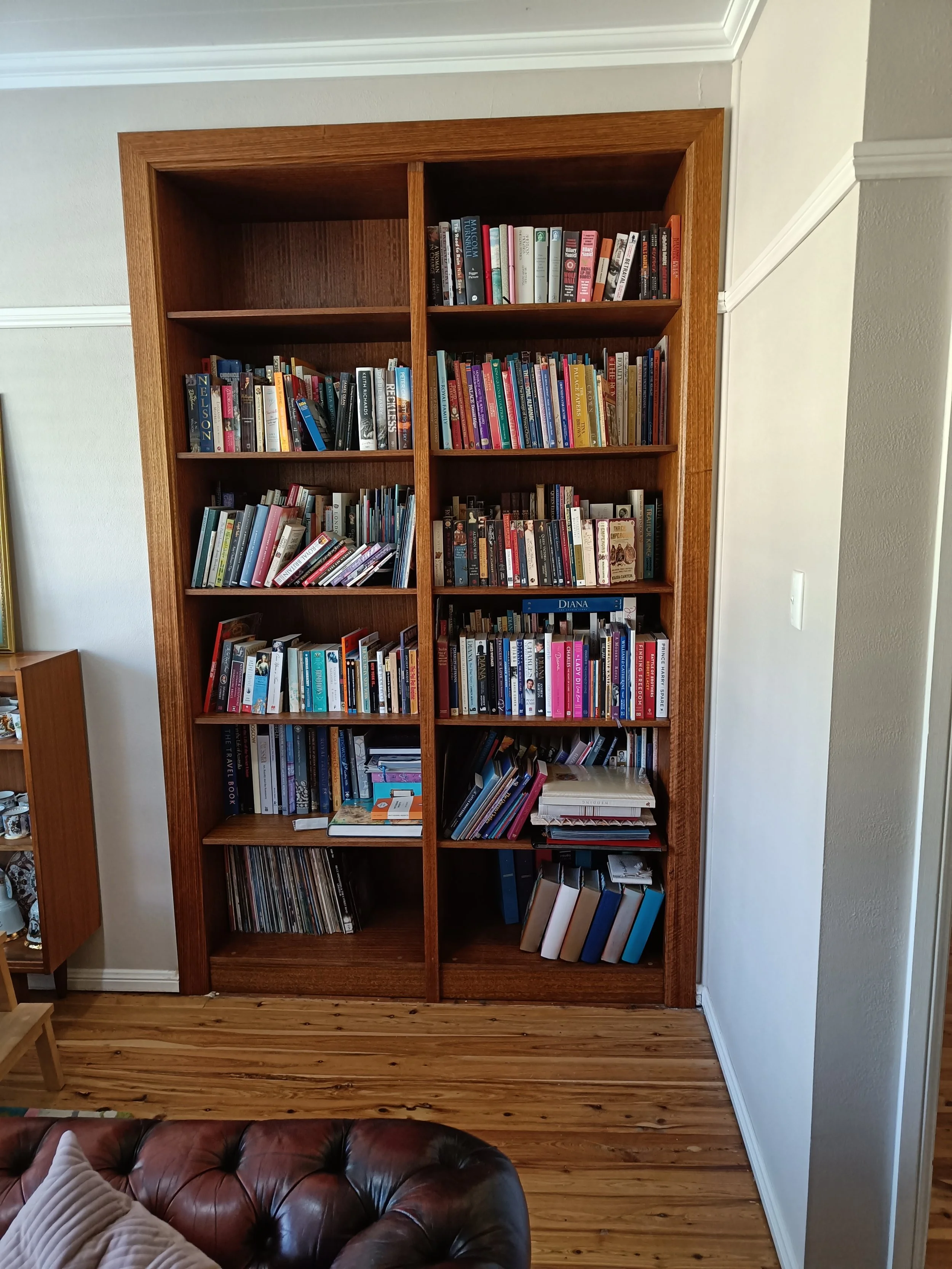 A wooden bookshelf filled with books in a living room.