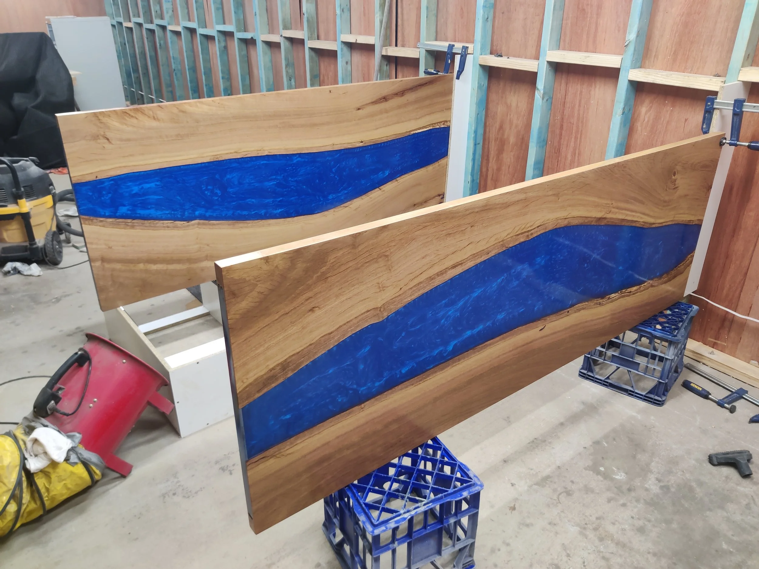Wooden panels with blue epoxy resin in a workshop setting.