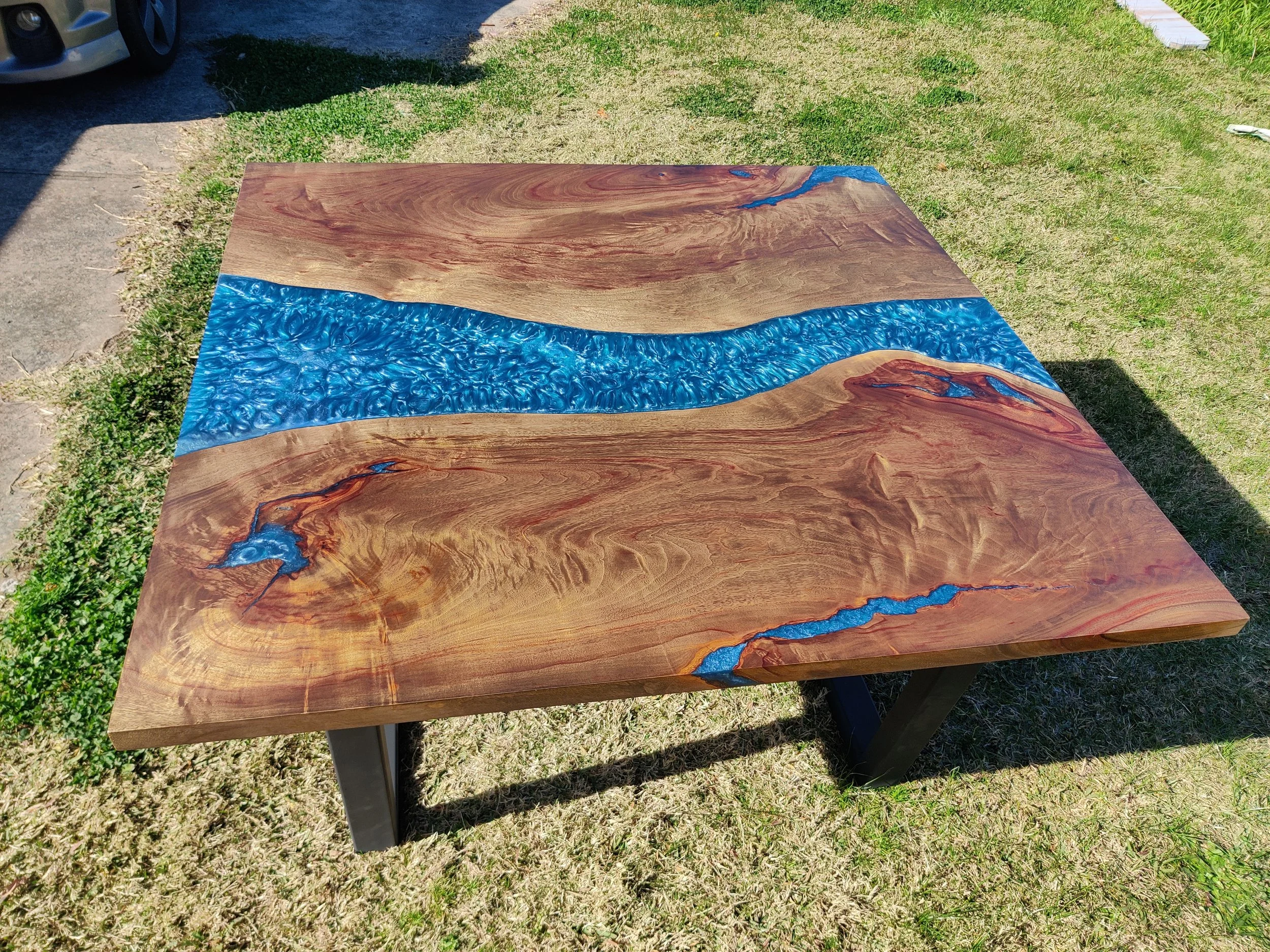 Wood and blue epoxy resin river table on grass