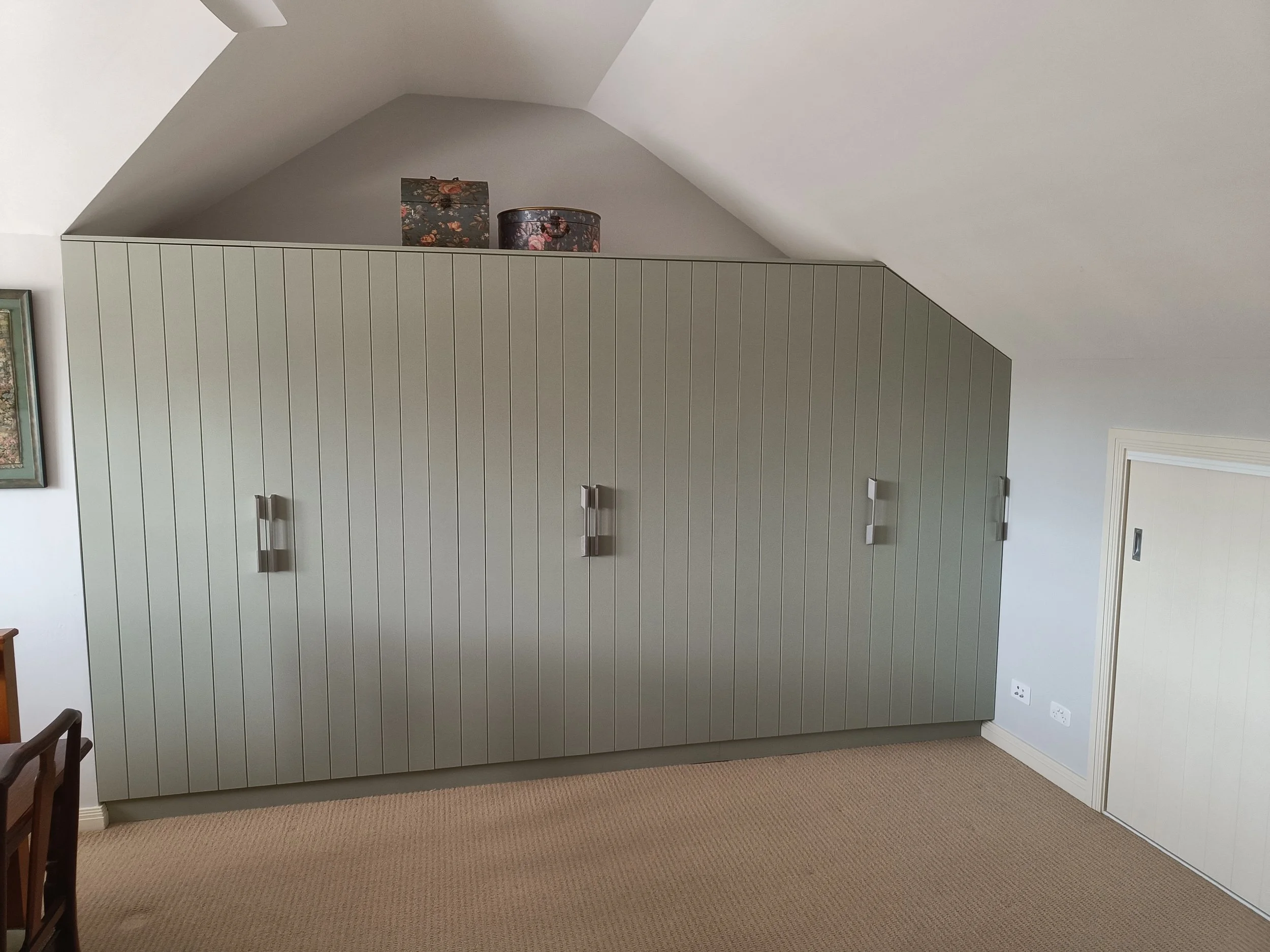 Room with green paneled closet and decorative boxes on top