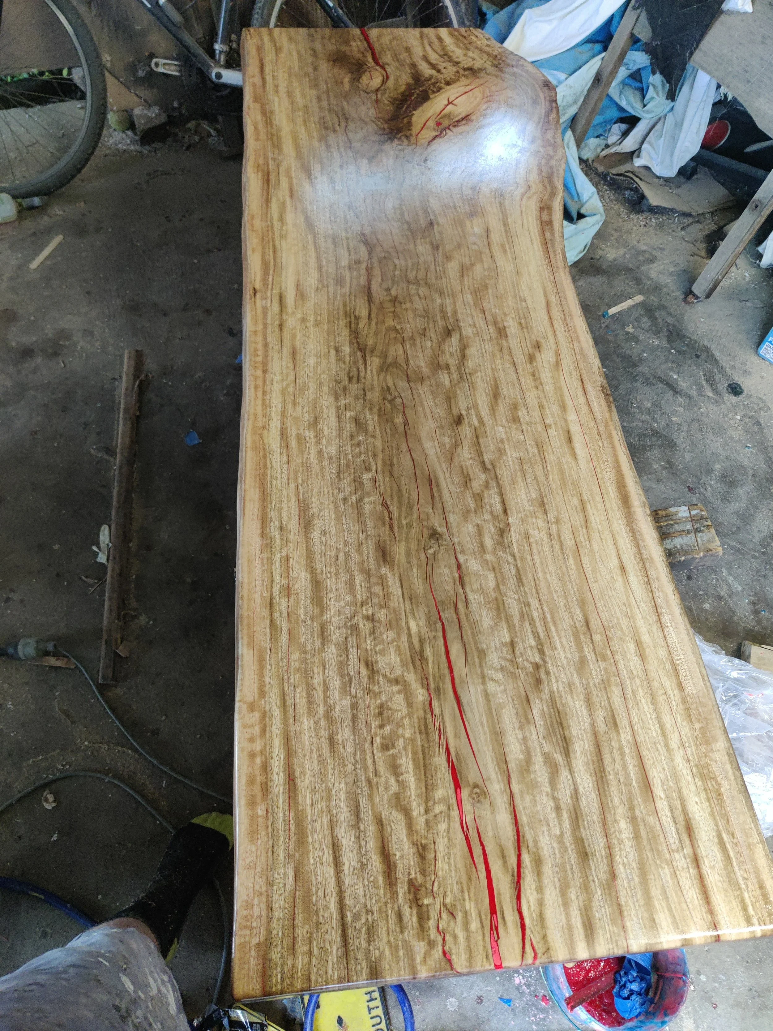 Wooden slab table with natural grain patterns and red epoxy resin accents.
