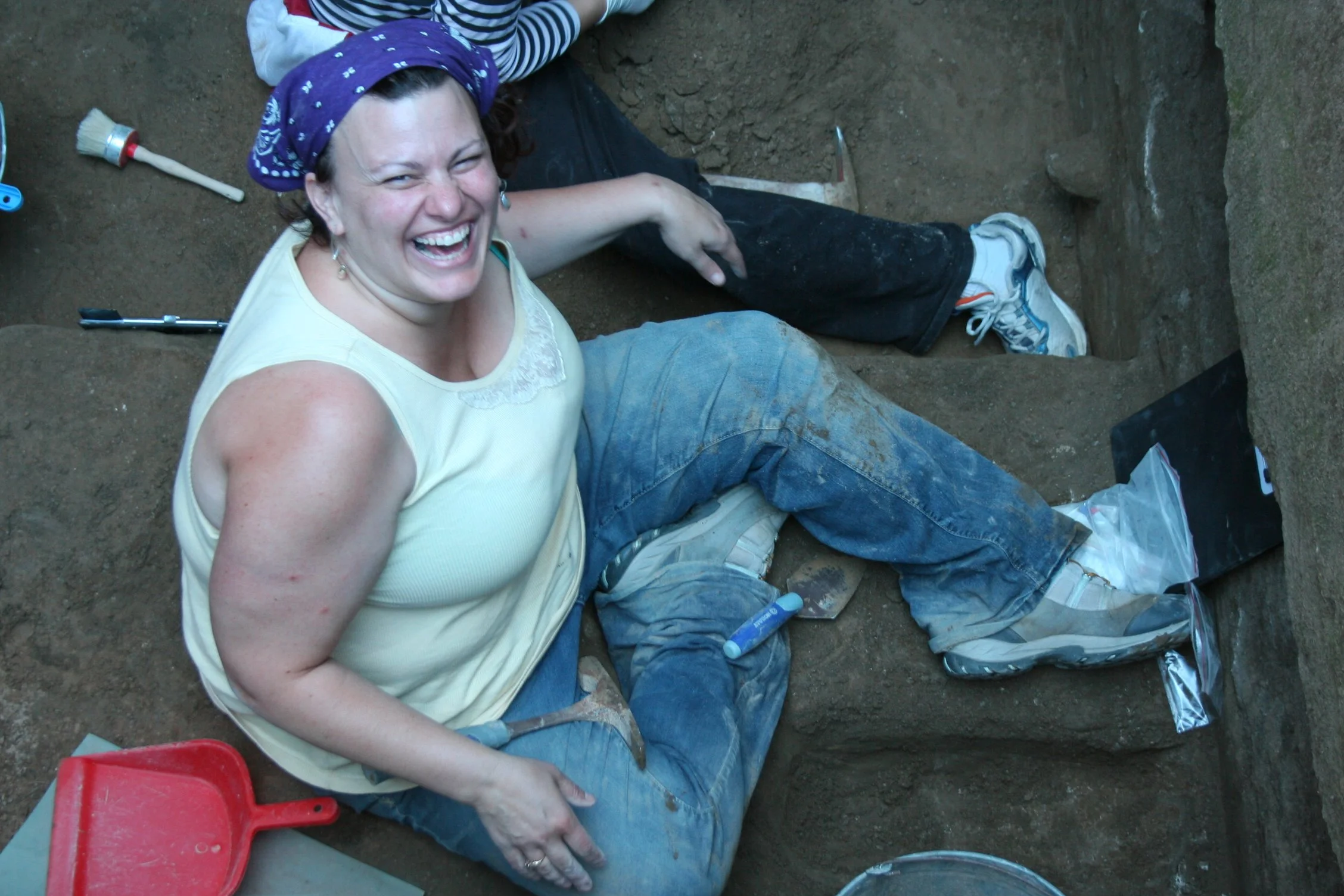Katrina covered in dirt and dust, laughing heartily while excavating. 