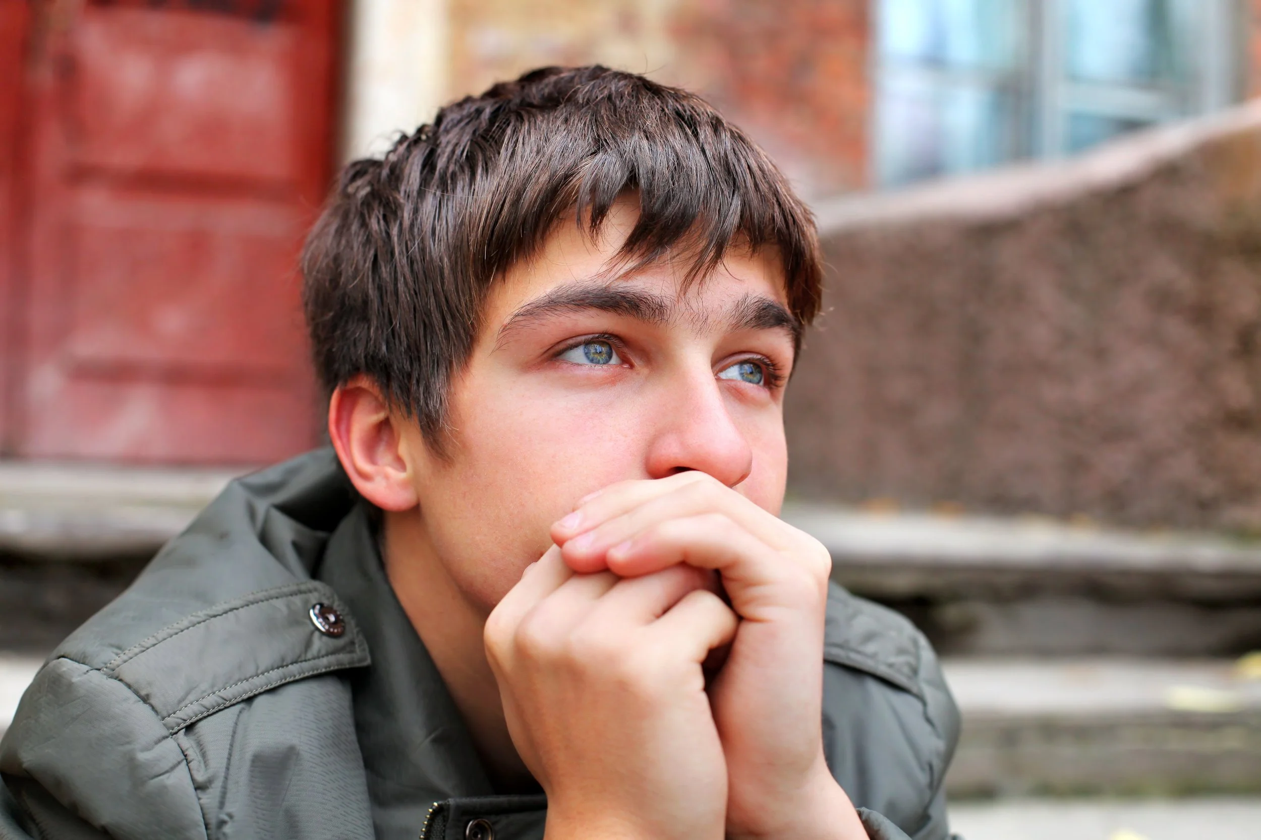 young boy sitting with hands close to face