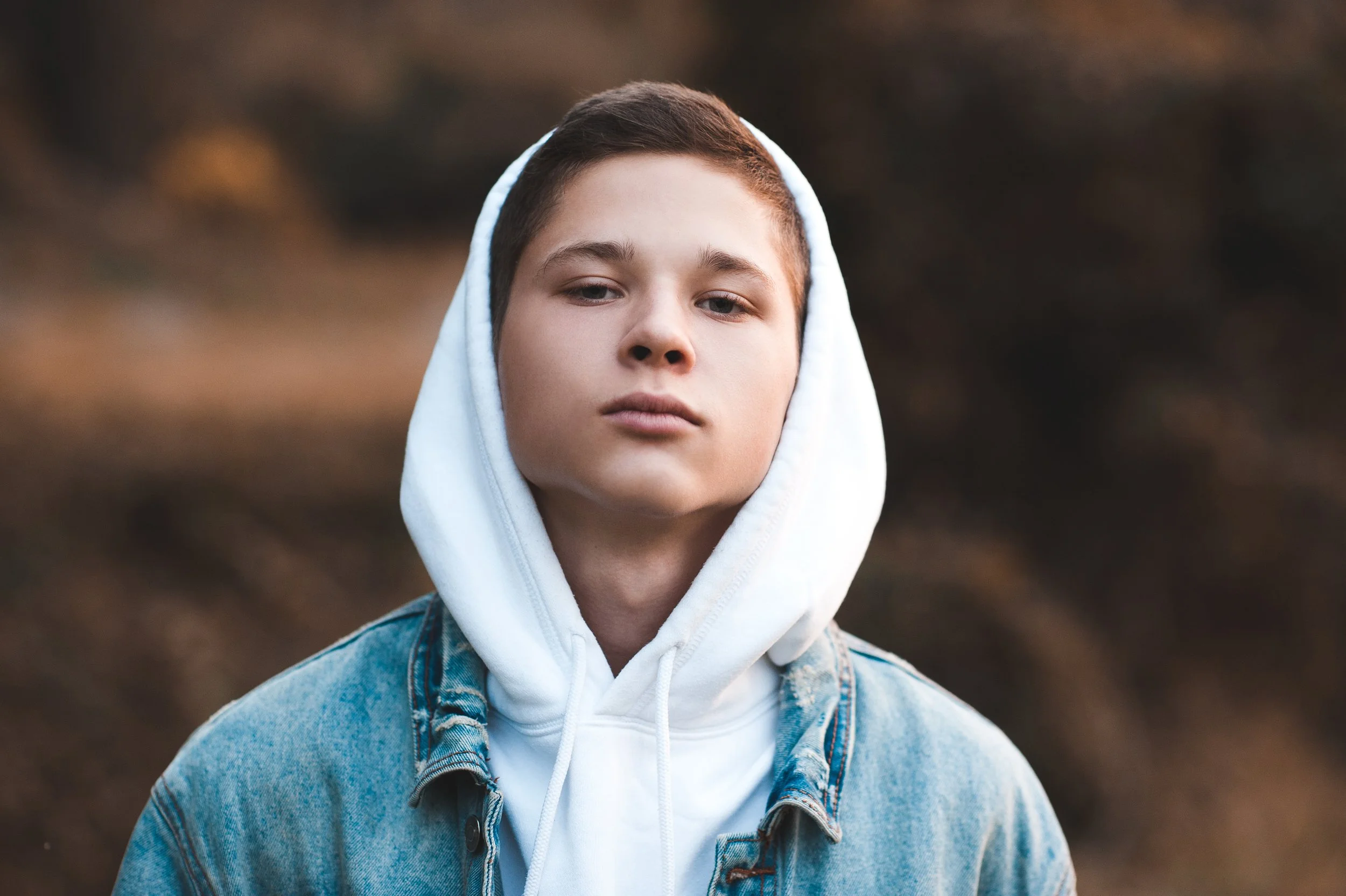 a young boy wearing a hoody and denim jacket