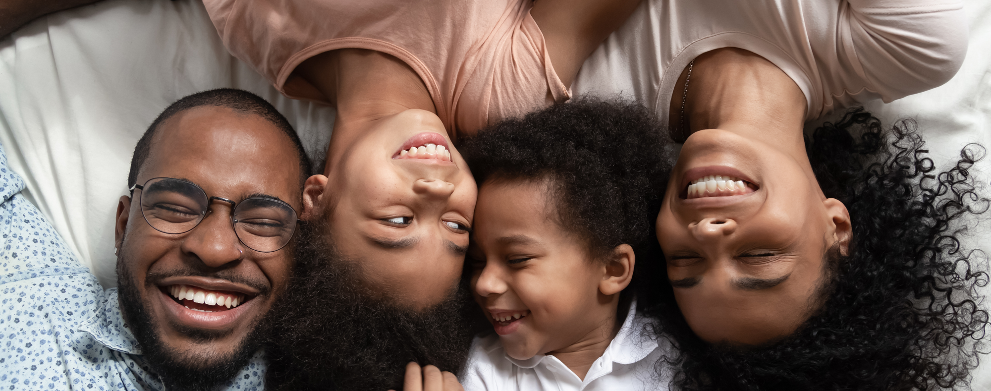 a family of four lying down with their heads next to each other smiling