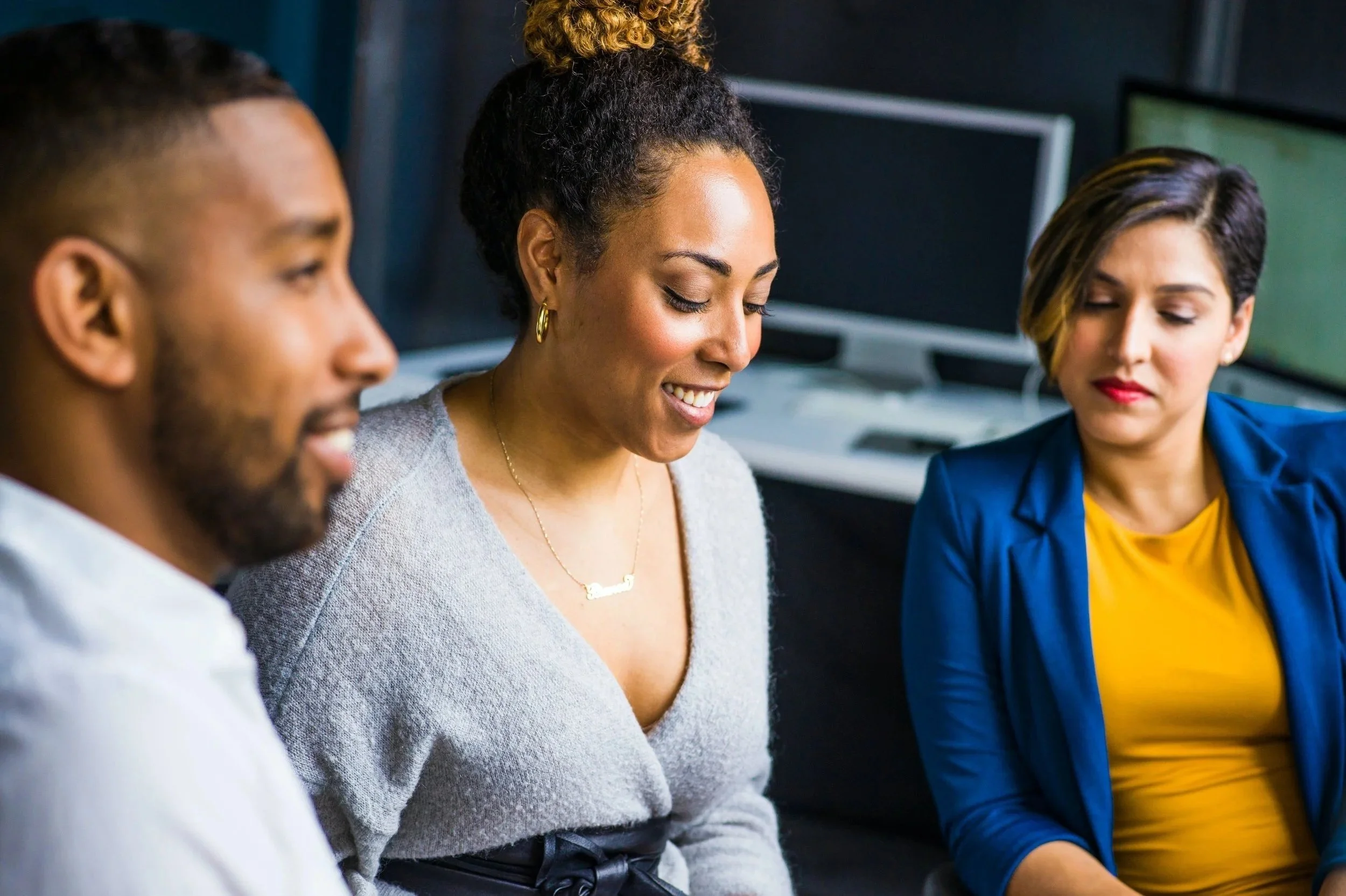 three people in a meeting looking at a laptop