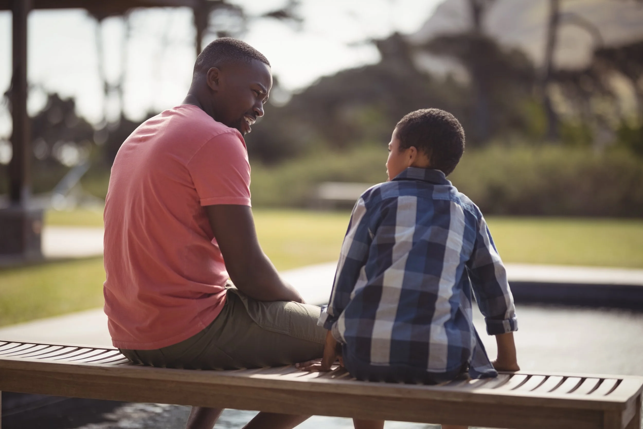 man and boy sitting on bench talking to each other