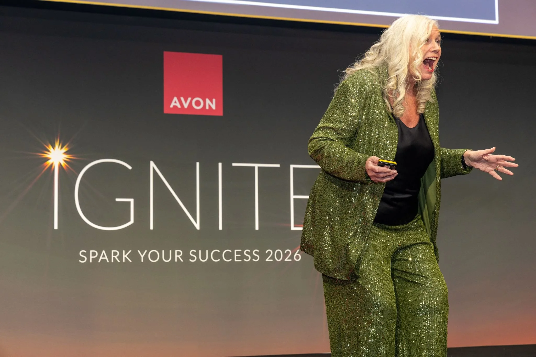 Dr Alison Edgar MBE on stage as a business speaker looking very excited and energised