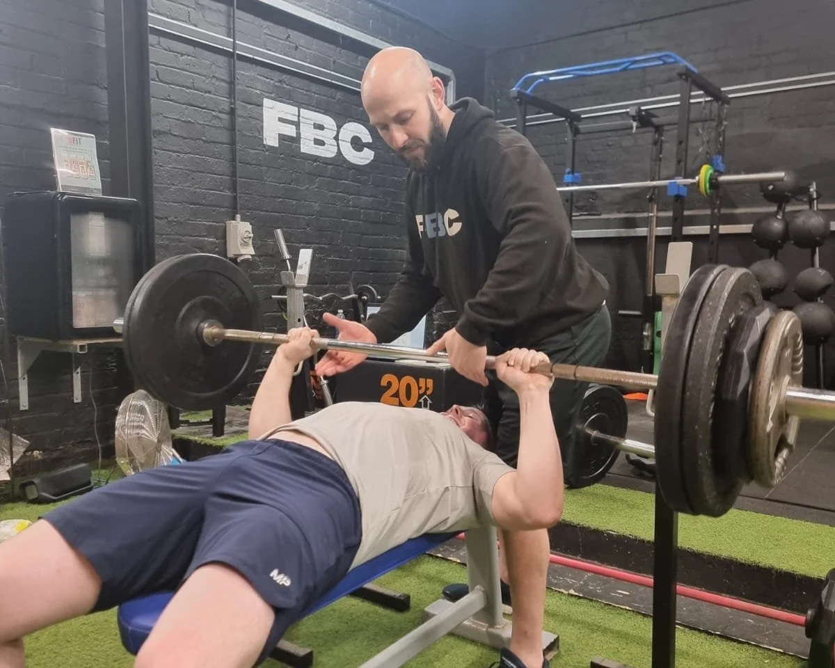 Dave Ward coaching a member during a bench press at FBC Harrogate