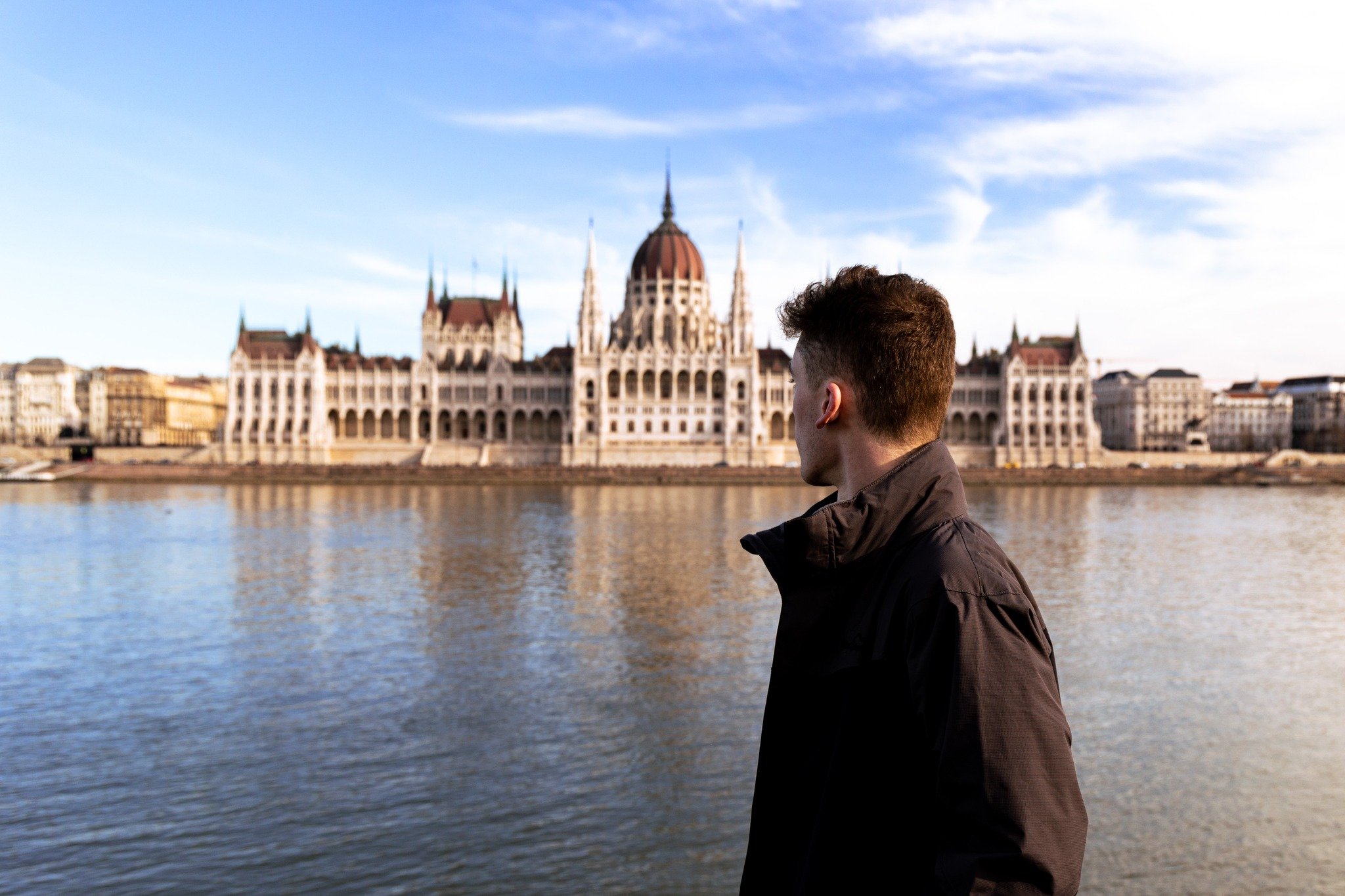 Man looking at the Hungarian Parliament Building across the Danube River in Budapest.