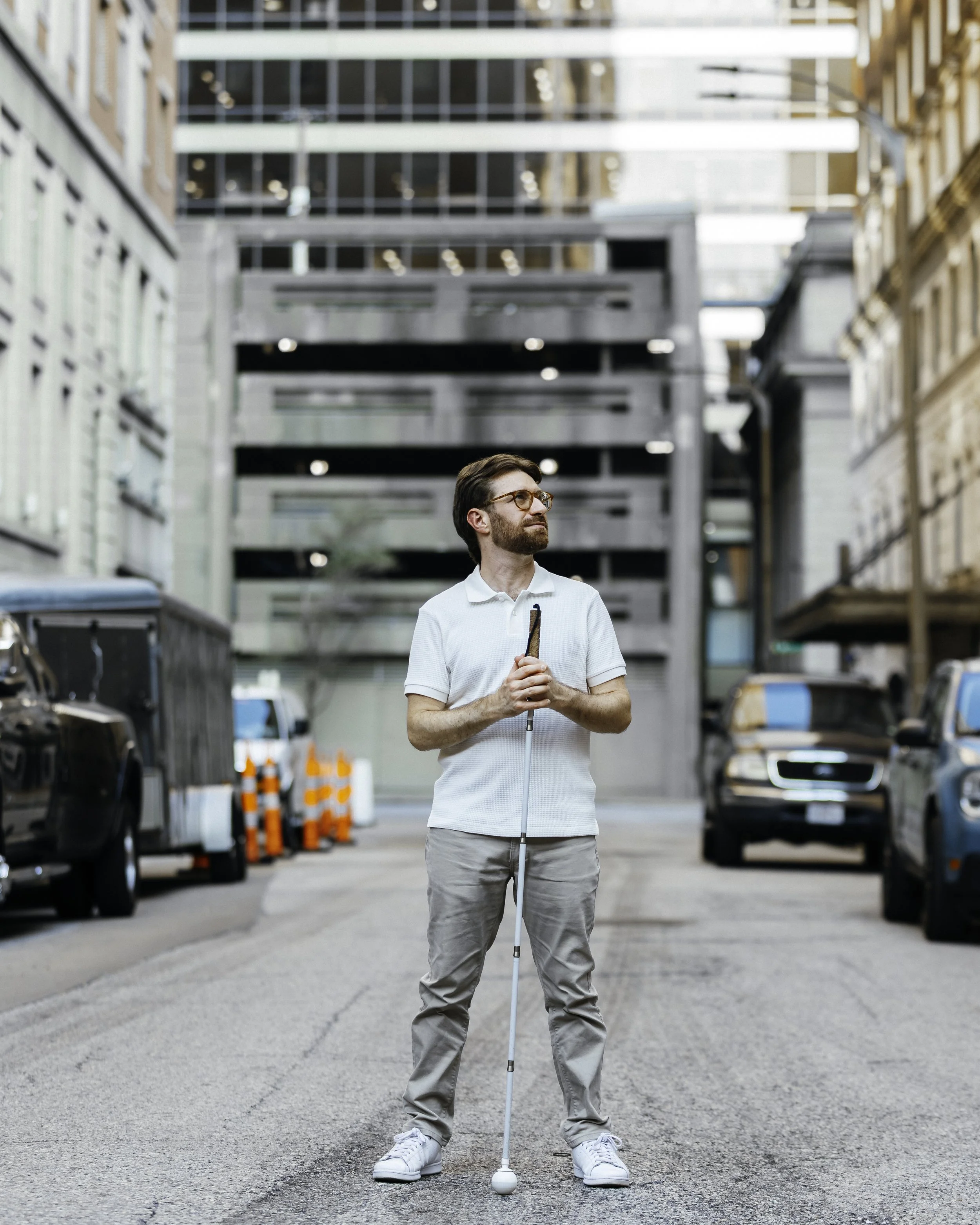 Charlie smiling and looking up while holding his cane in a city