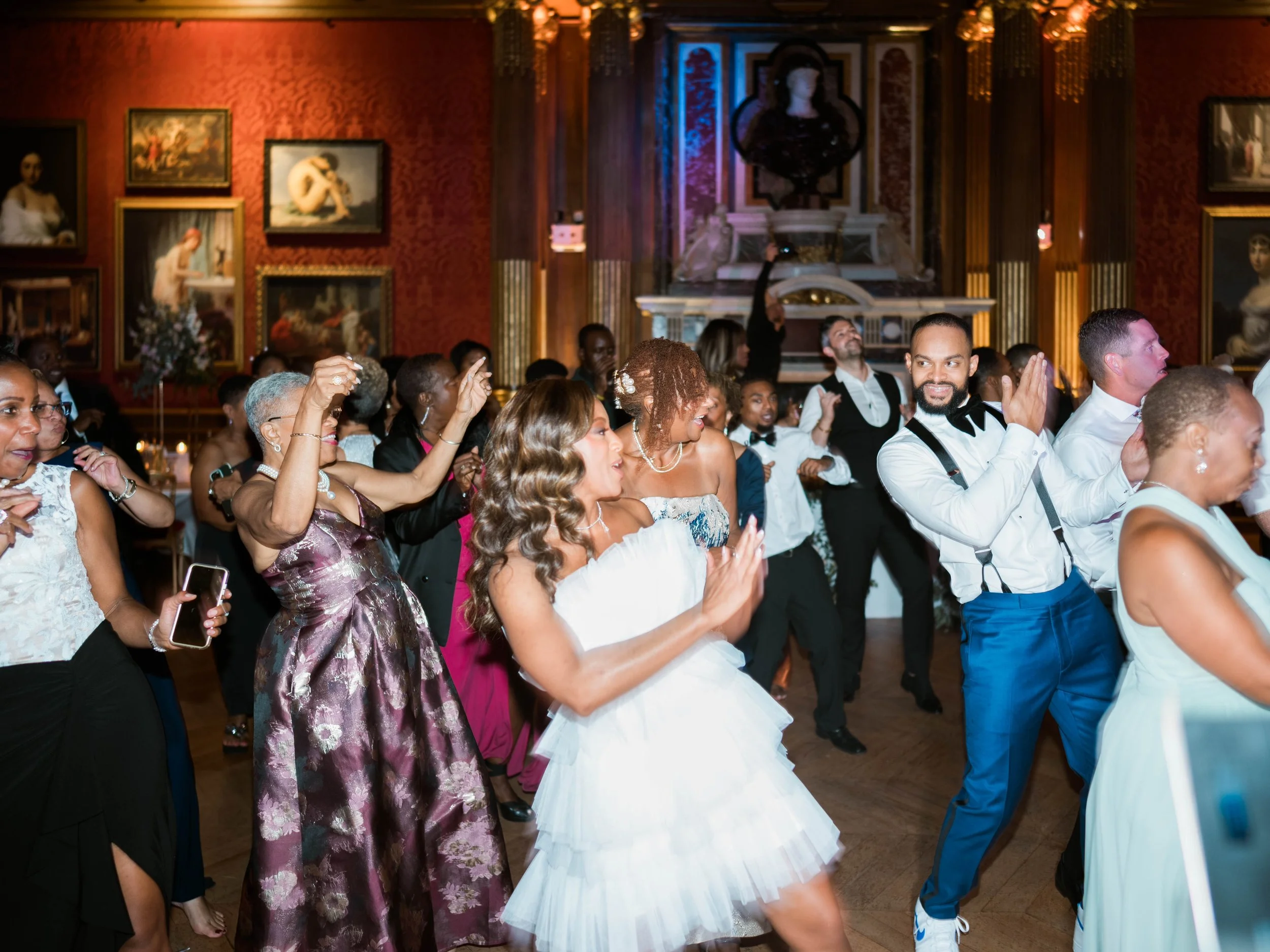 Groupe de personnes dansant lors d'une fête élégante avec des œuvres d'art en arrière-plan.