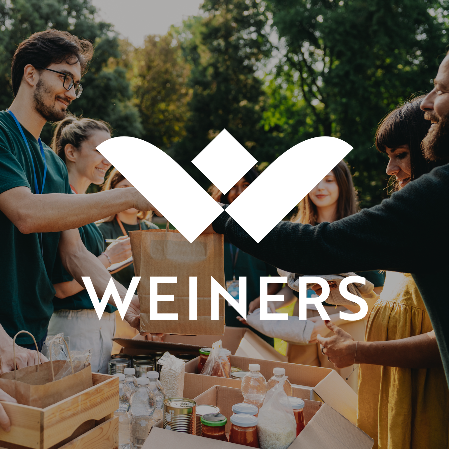 A group of people outdoors, smiling, exchanging items or food, with a large Weiners logo overlay on the image.