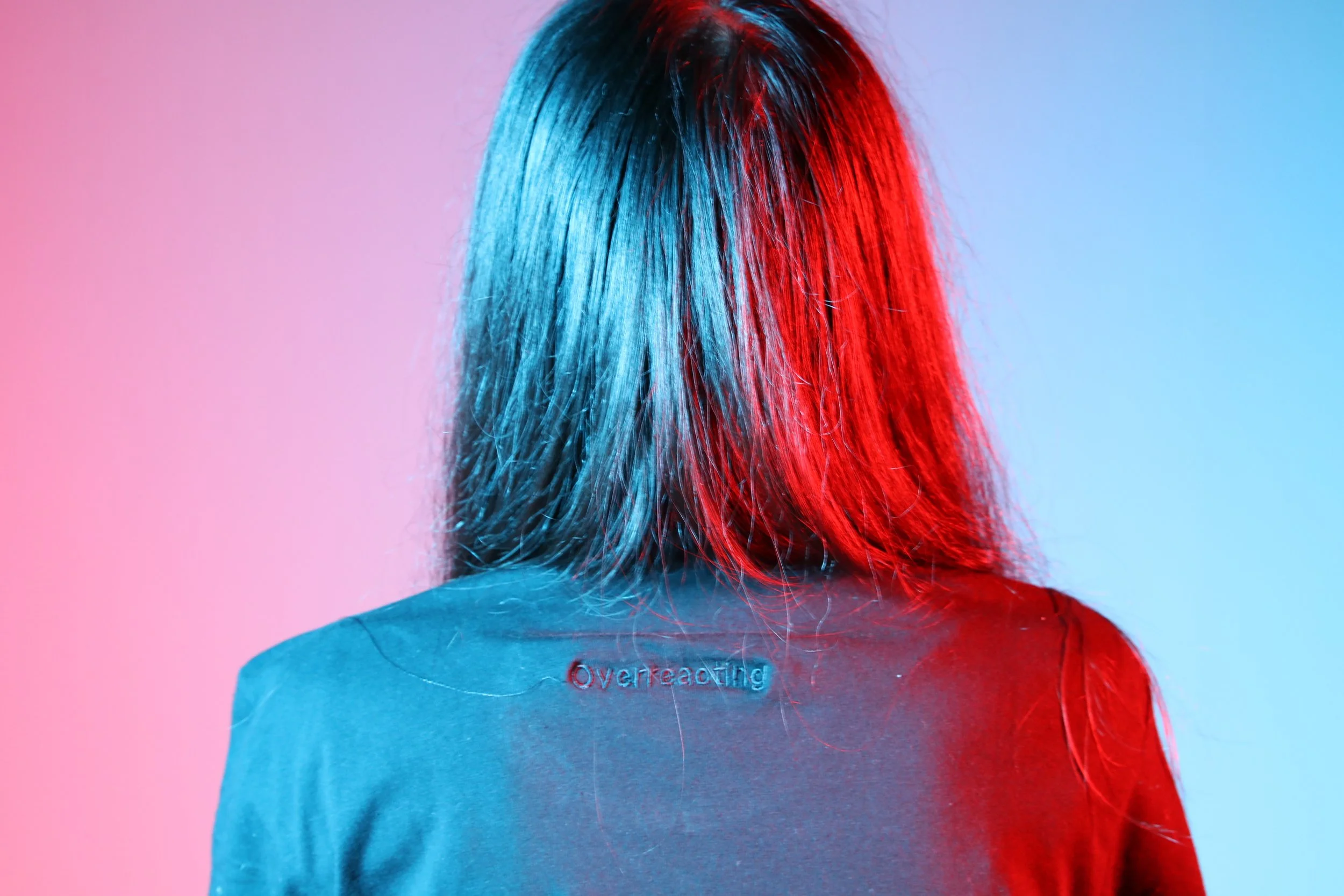 Back of a girl wearing a tshirt, 'overreacting' embroidered onto it.