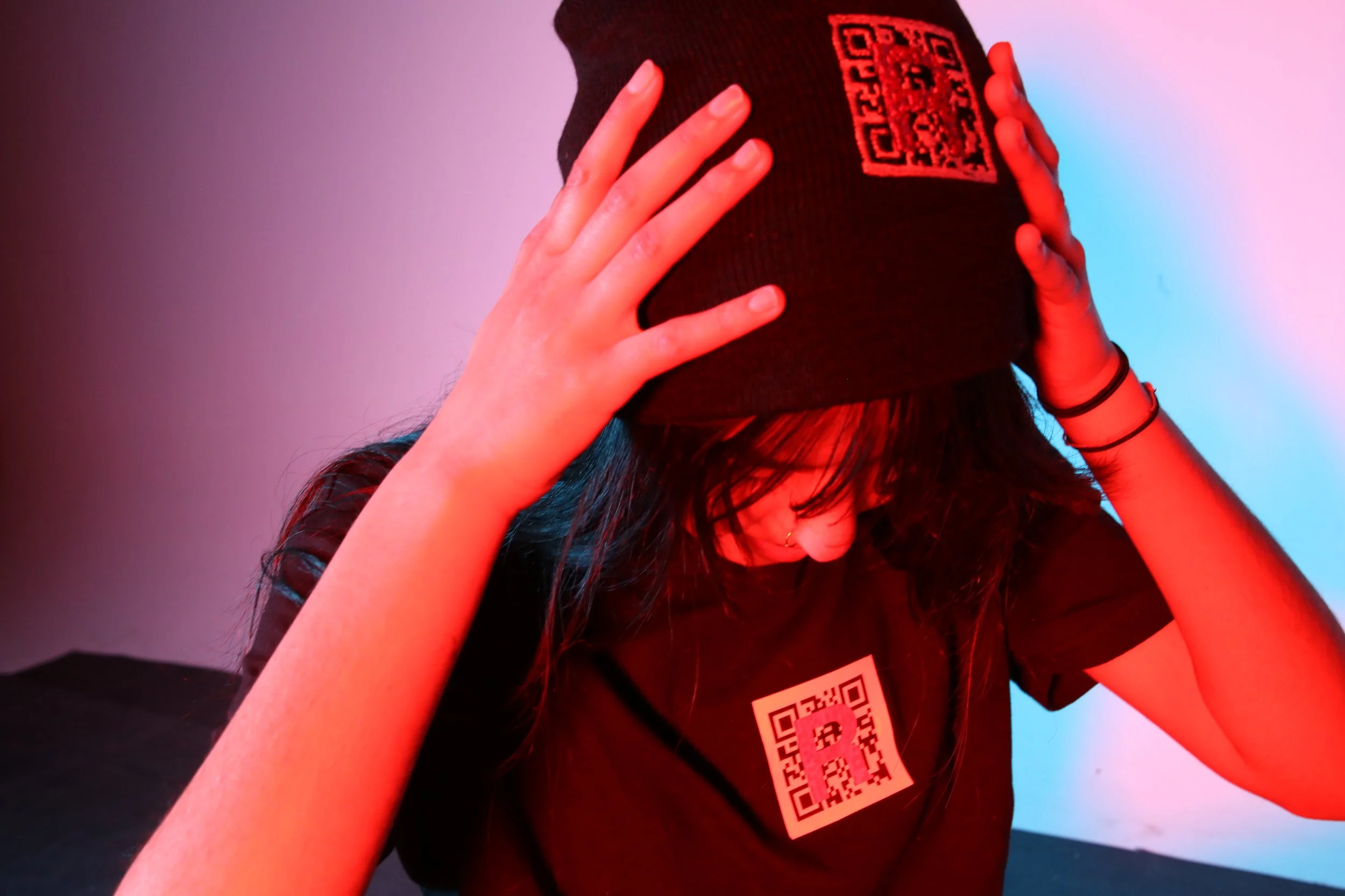 Girl wearing a tshirt and beanie hat with 'R' QR code logo. 