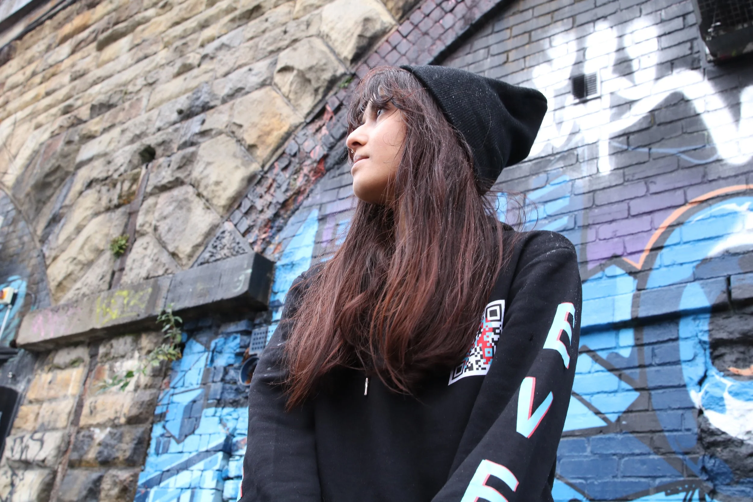 Girl wearing a beanie and hoodie with 'R' QR code logo.