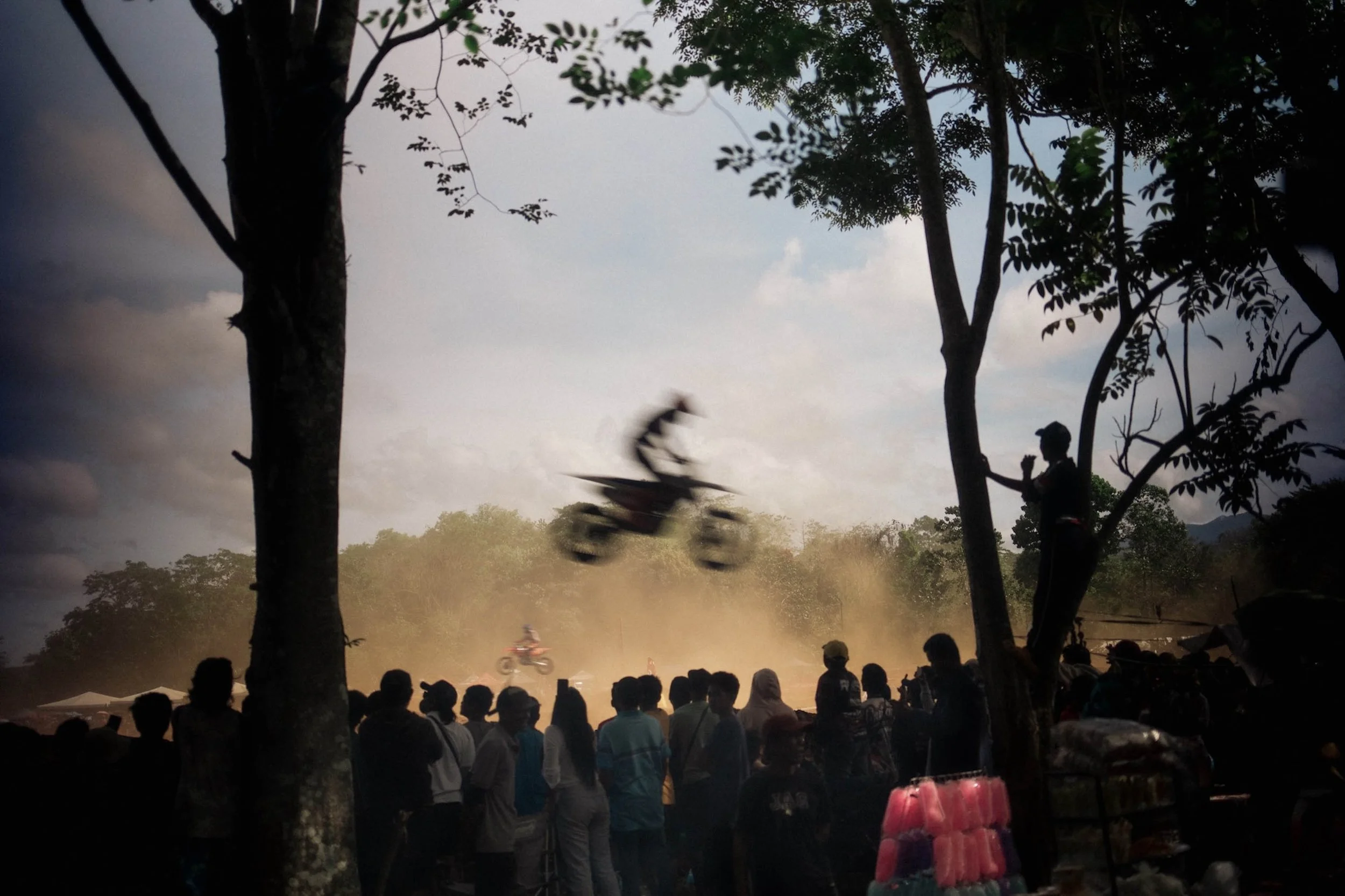 A motorbike rider in mid-air framed by trees, cinematic portraits inspired by Bali photographer