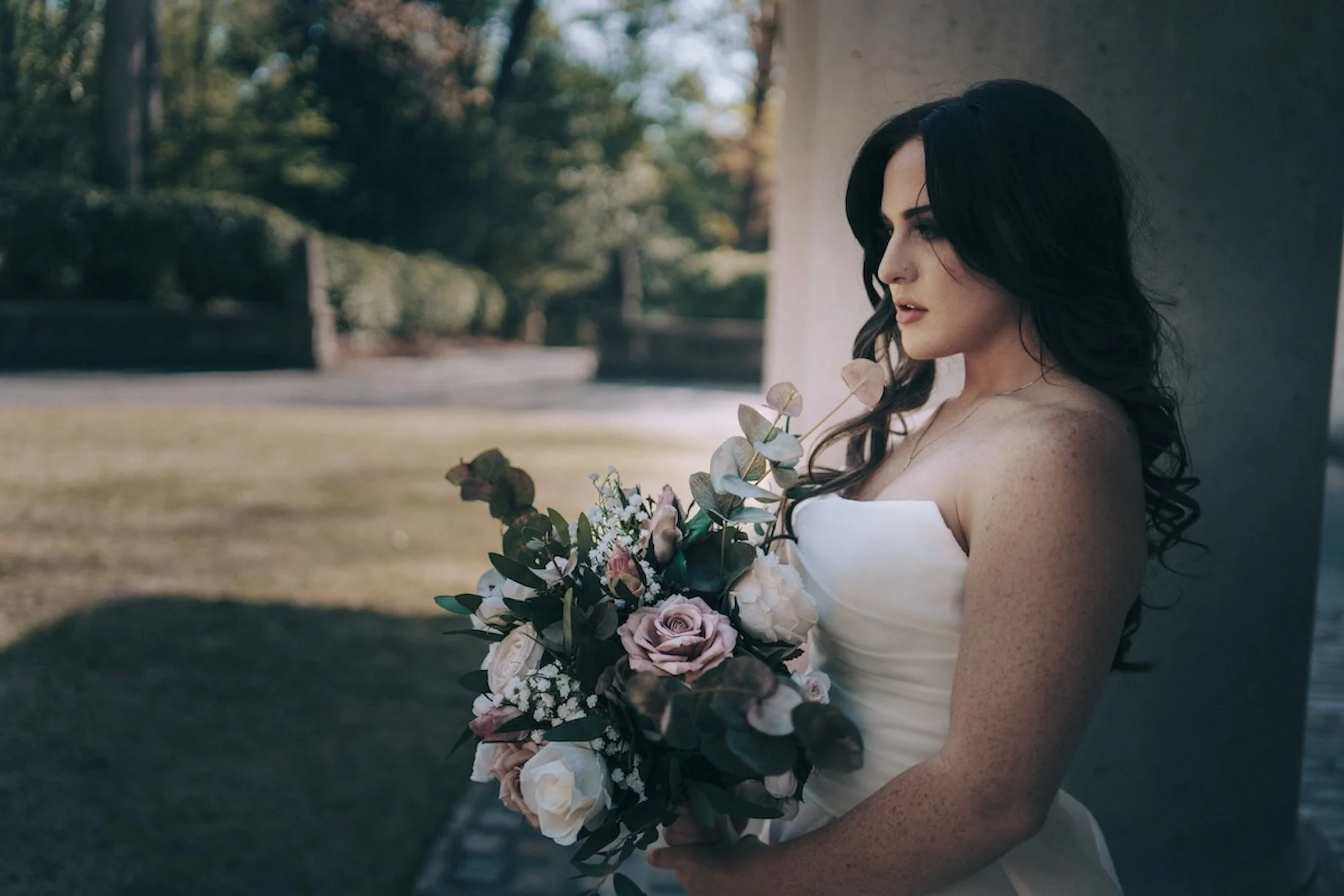 A bride stands with bouquet in hand, side profile catching the light, her expression both serene and strong in this Kyoto inspired wedding setting.