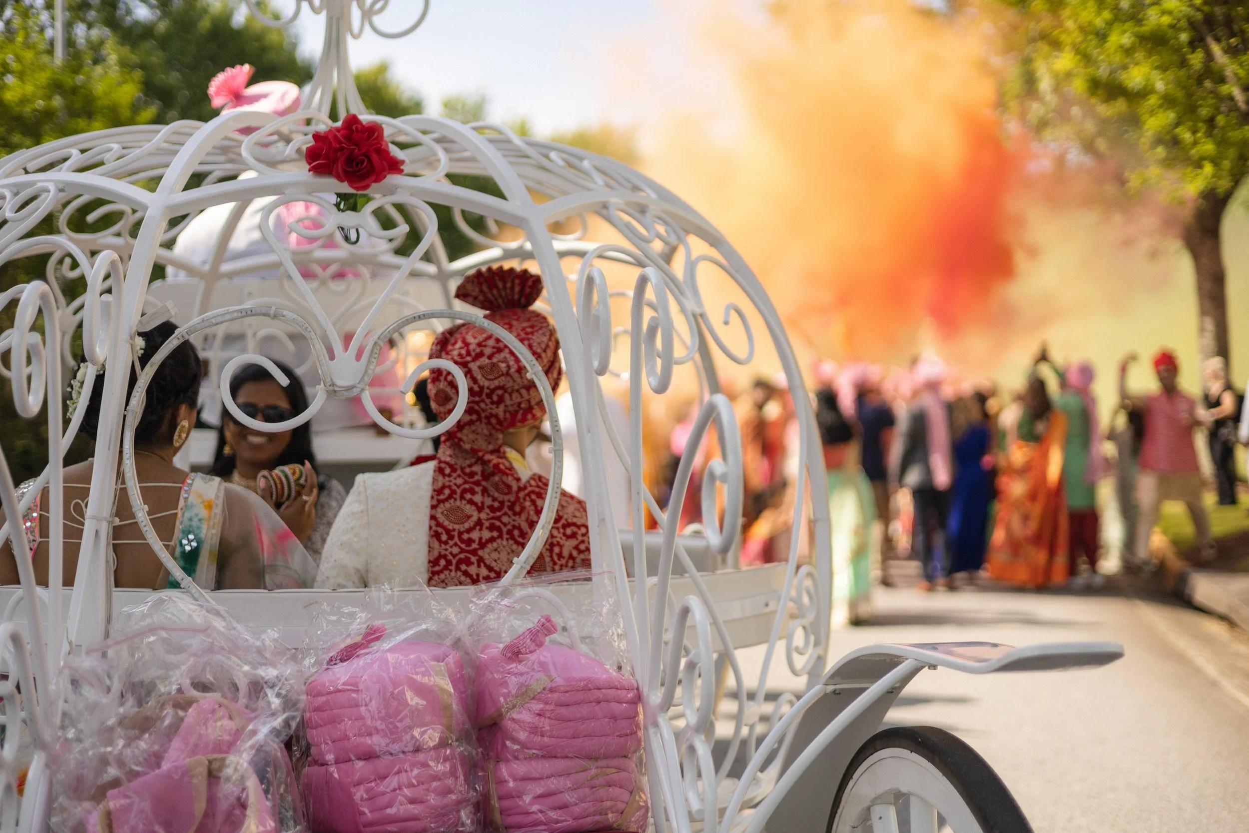 A white horse-drawn carriage adorned with red and pink florals arrives for the wedding procession, captured by India Wedding Photographer Caz Isaiah