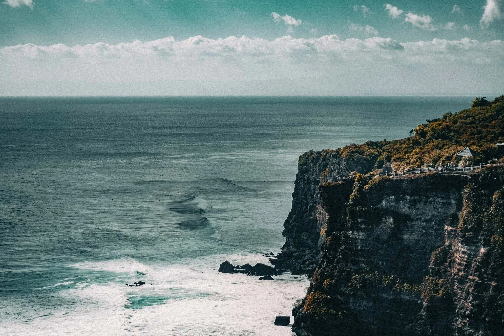 Ocean waves crash against towering cliffs, echoing the atmosphere of a coastal Uluwatu wedding.