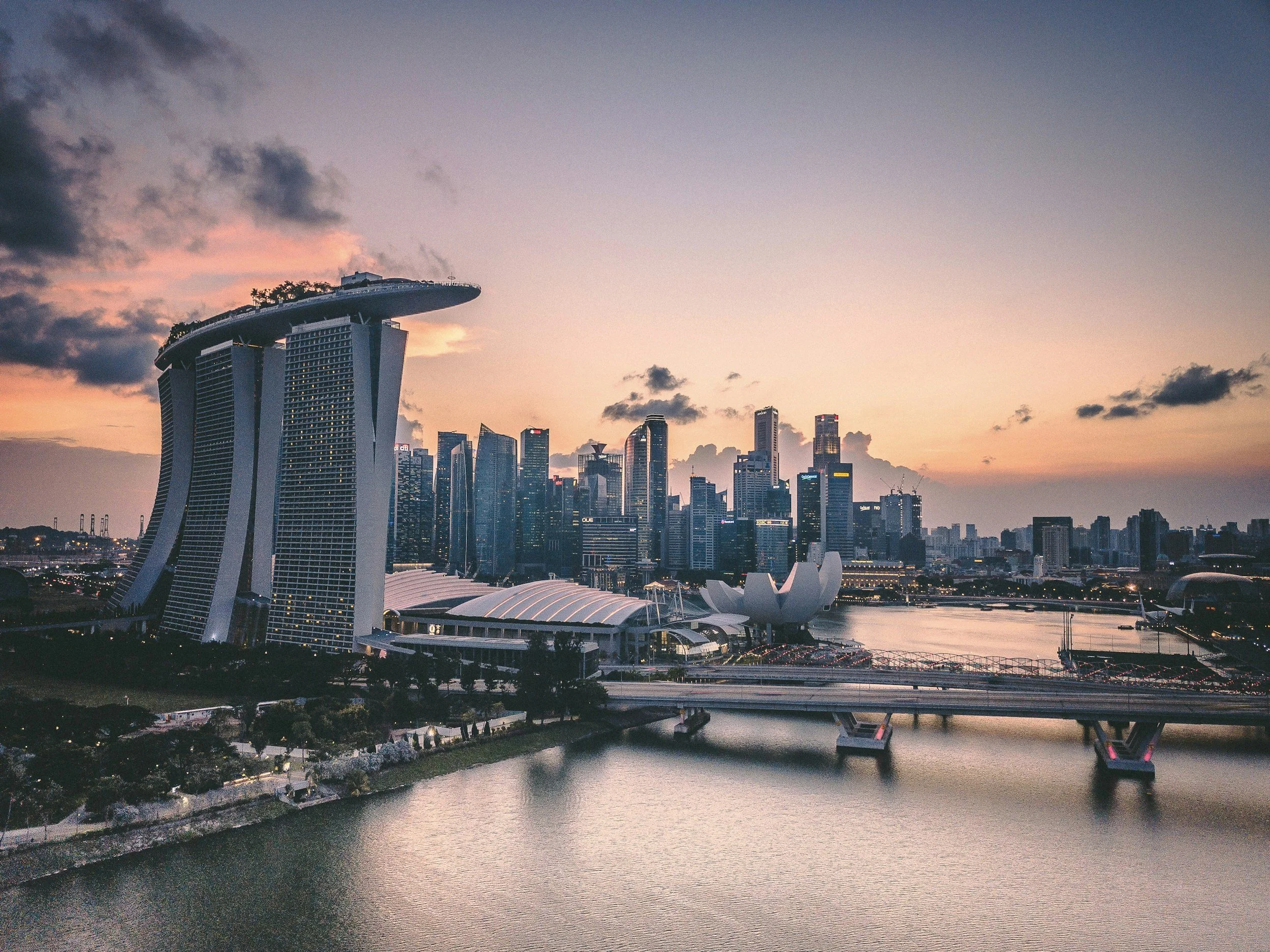 Singapore’s skyline glows at dusk above calm water, towers catching the last light in a composition that feels like a cinematic couples film frame.