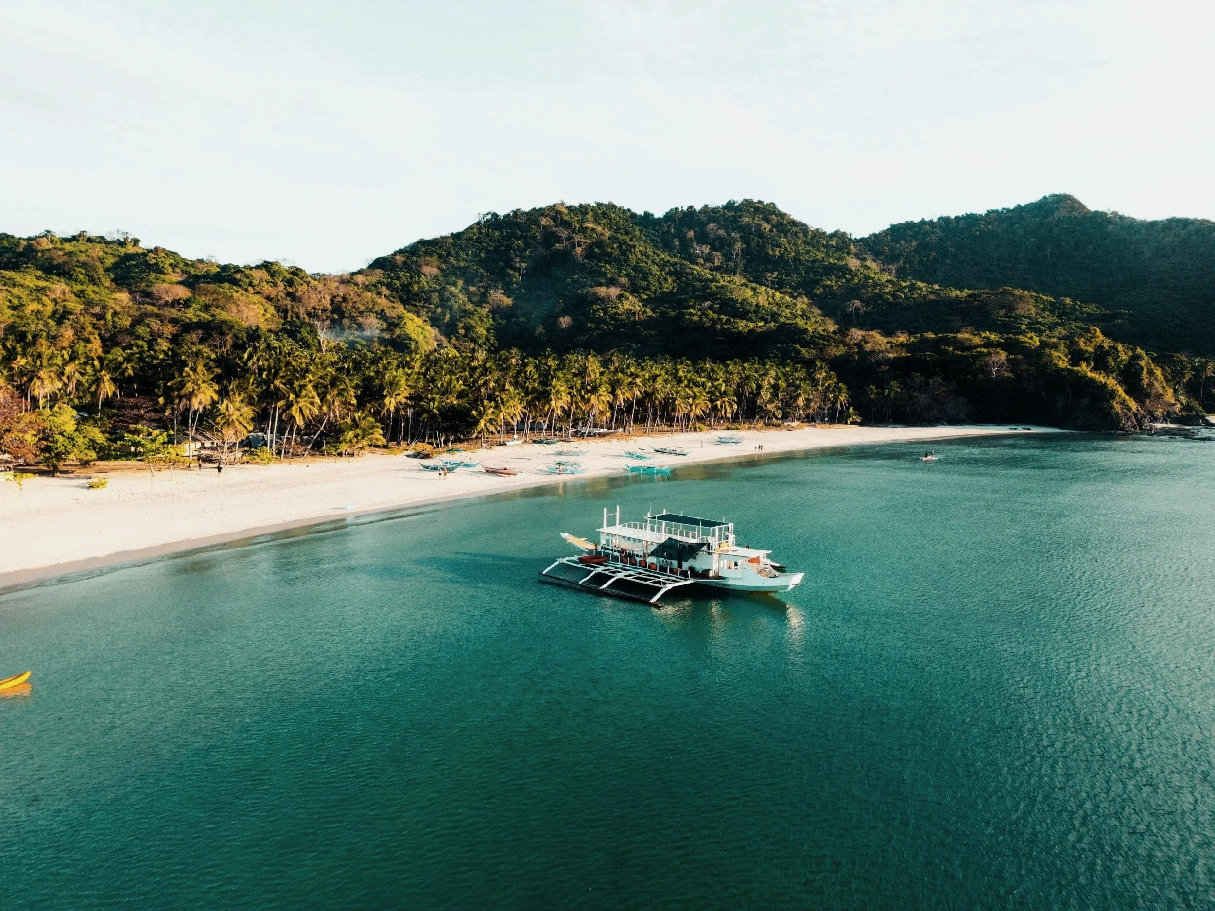 A boat floats motionless near a shoreline, water shifting in soft patterns beneath it as light settles across the frame.