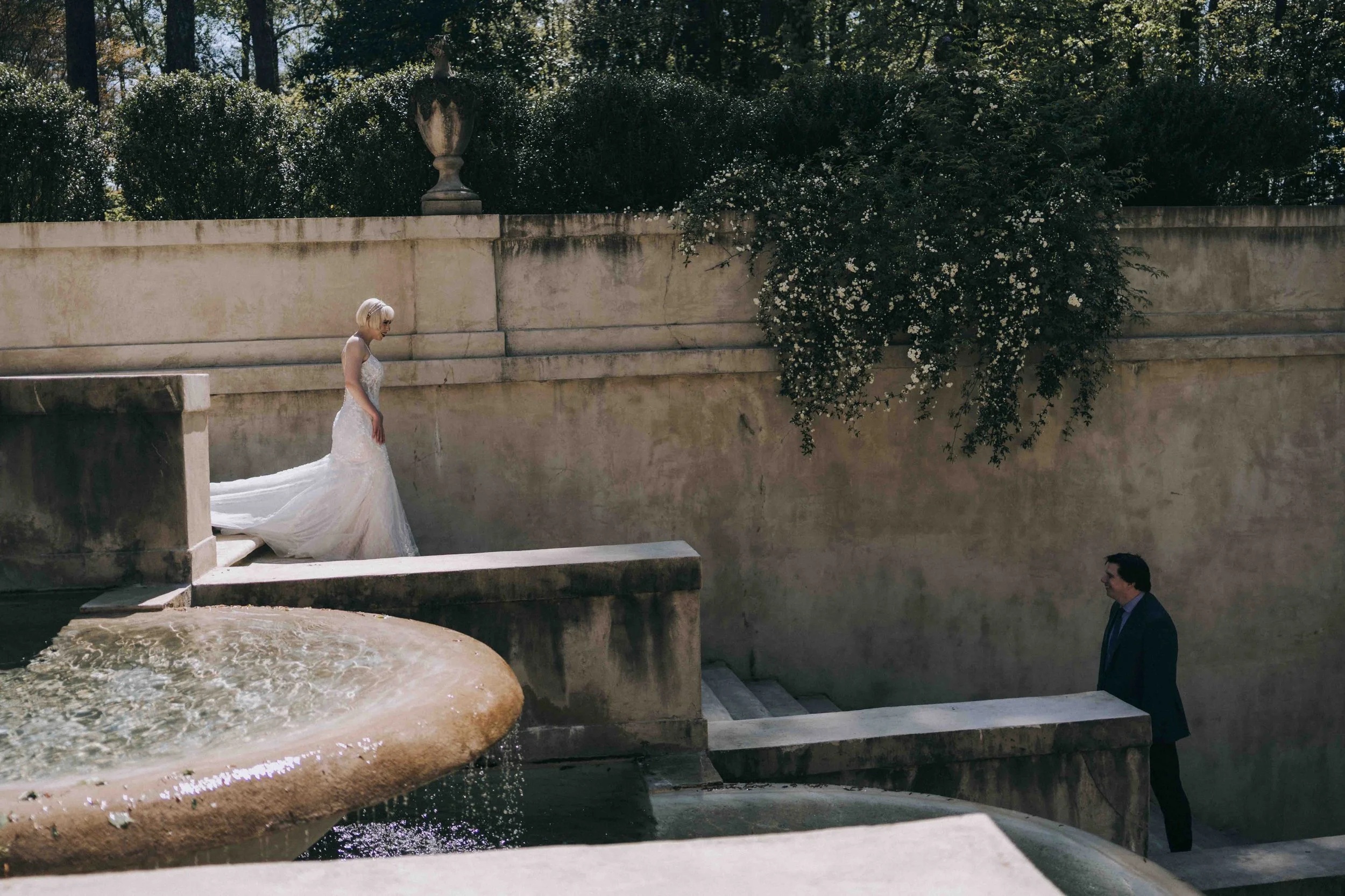 Bride descends marble steps toward the groom, her gown trailing softly through sunlight — inspired by Habitas AlUla Wedding Photographer style.