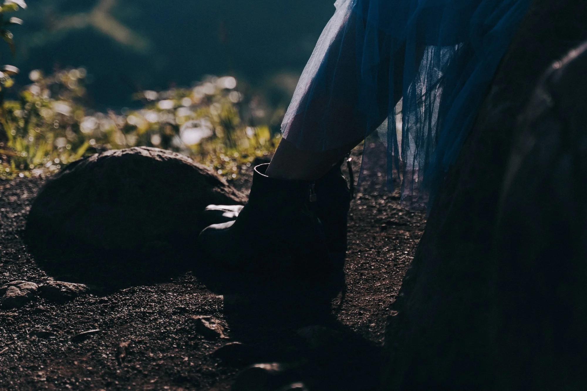 Close-up of boots on stone, cinematic textures and shadows grounding the frame with raw editorial detail