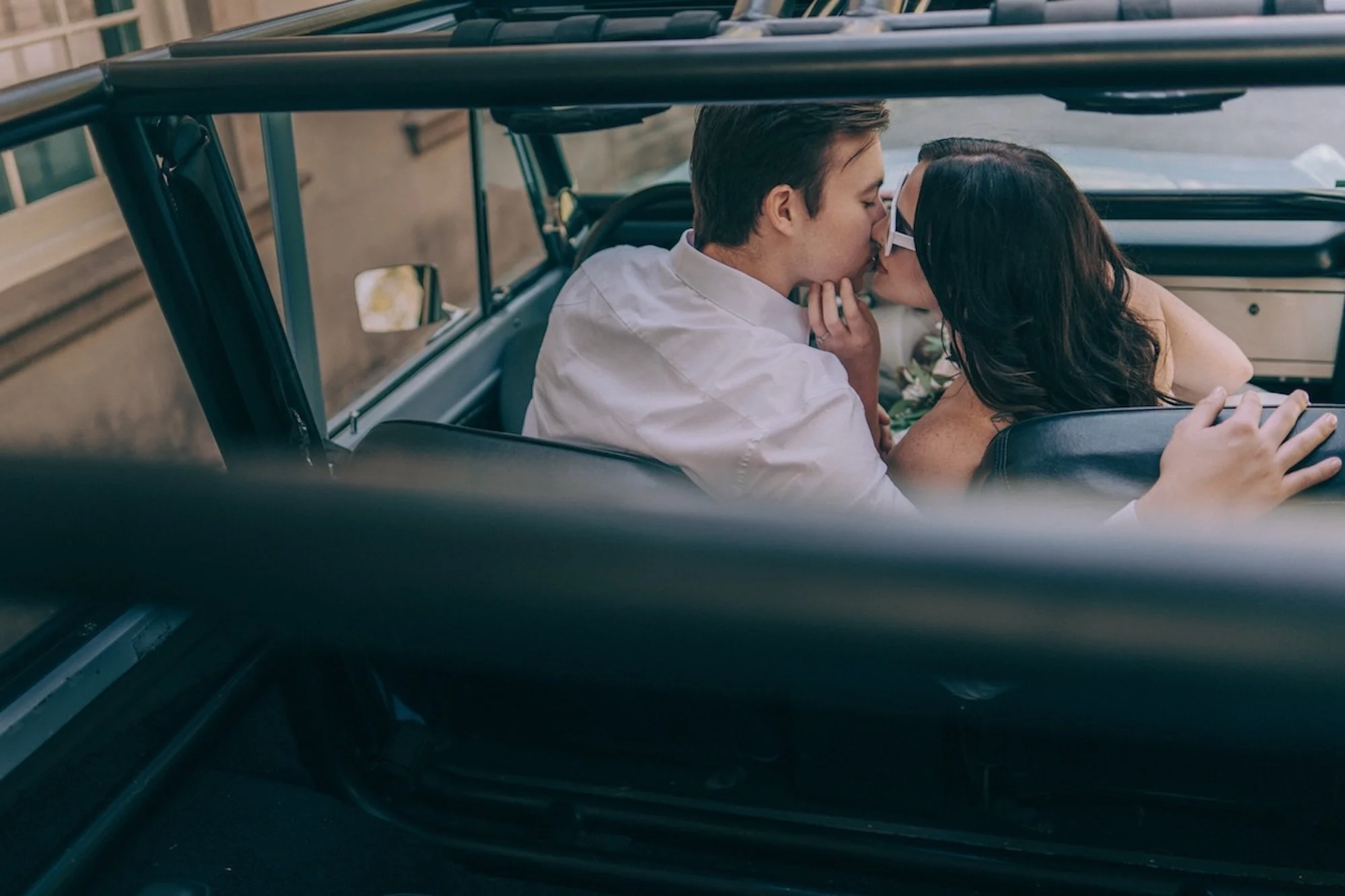 A couple shares a kiss inside a classic car, a scene filled with intimacy and elegance, perfectly told through the eye of a Kyoto Wedding Photographer.