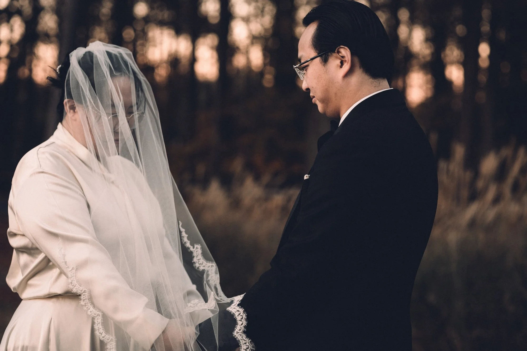 A groom lifts the veil from his bride’s face, a tender moment framed with soft golden light, captured by a Kyoto Wedding Photographer.