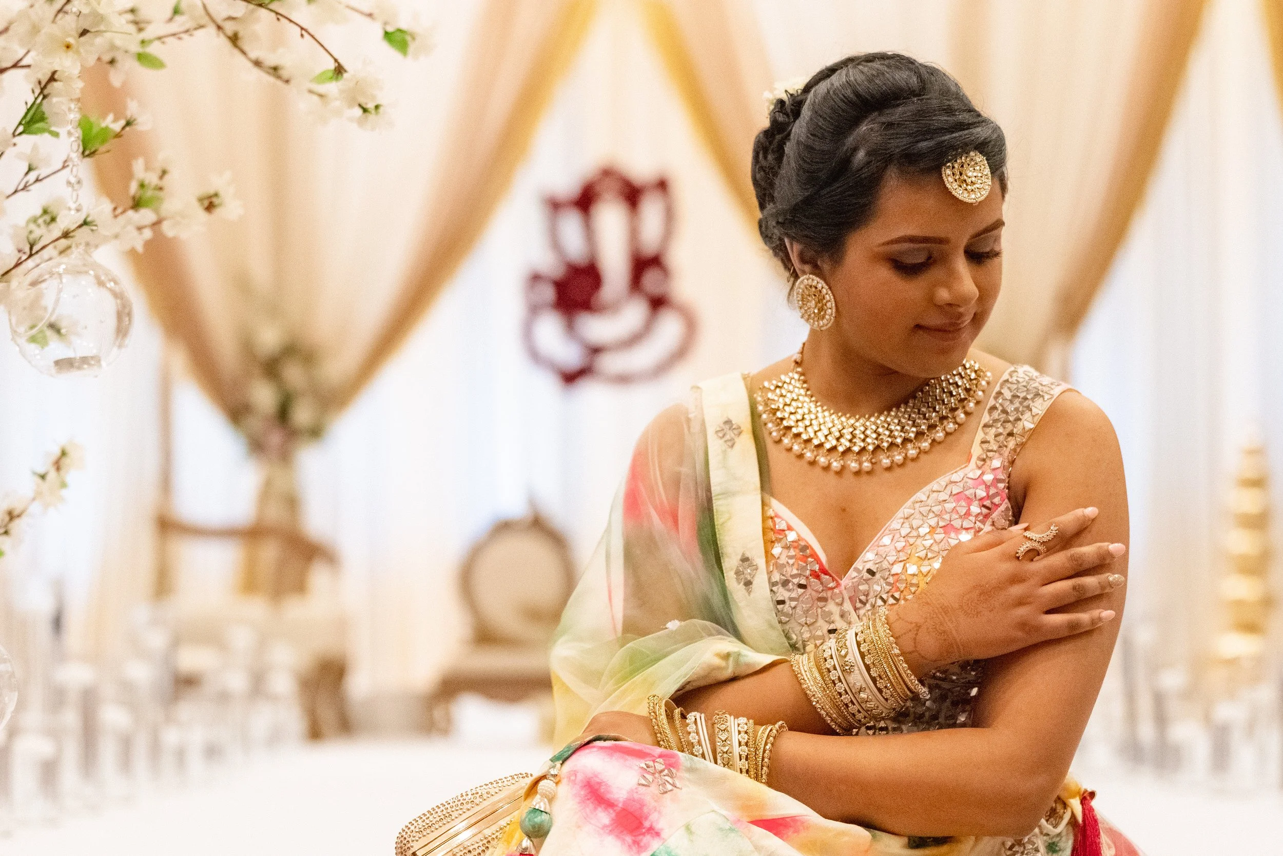 Bride seated in an elegant lehenga with floral décor surrounding her, editorial portrait captured by Caz Isaiah — India Wedding Photographer