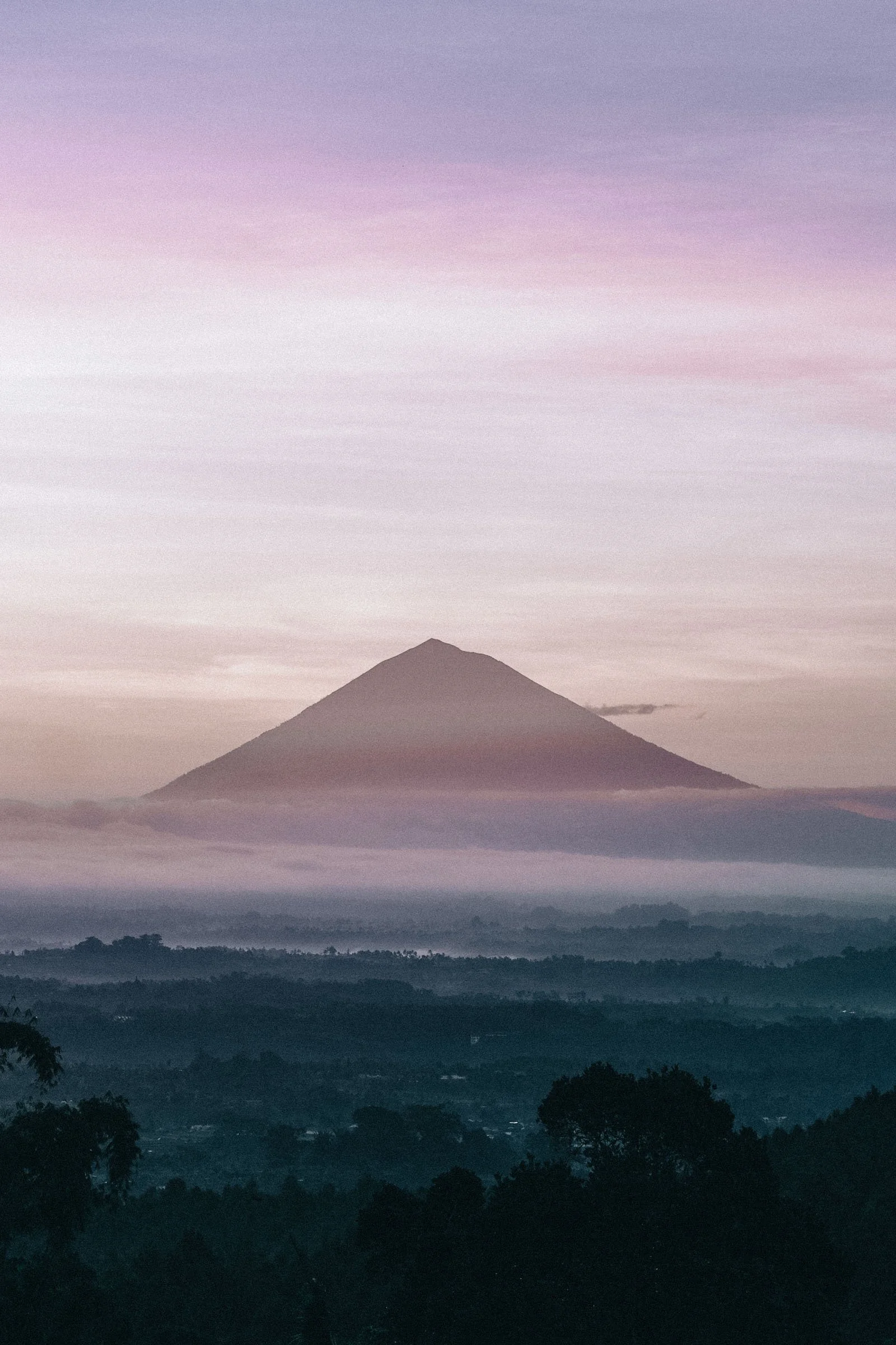 A mountain peak rises above morning mist, a cinematic backdrop reminiscent of vows in Bali