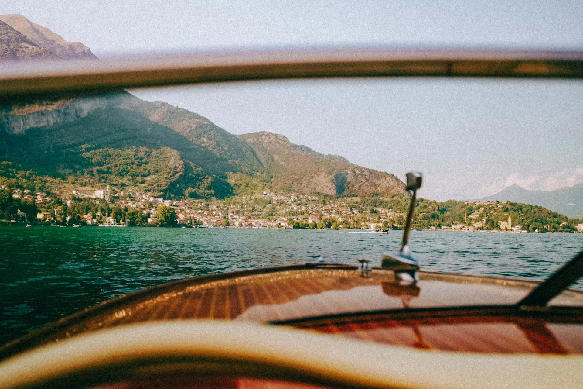 View across Lake Como from a classic wooden boat, framed by cinematic waterside scenery that defines luxury Italian weddings.