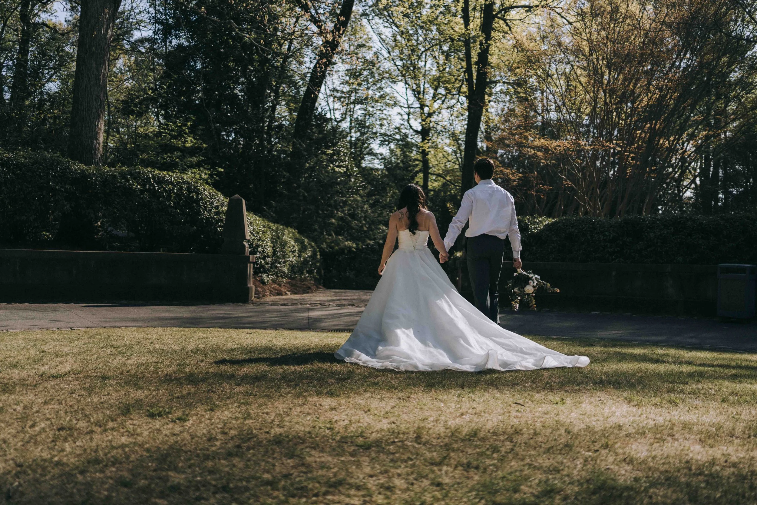 Bride and groom walking hand in hand through sunlit gardens — captured by The Edge Bali Wedding Photographer.